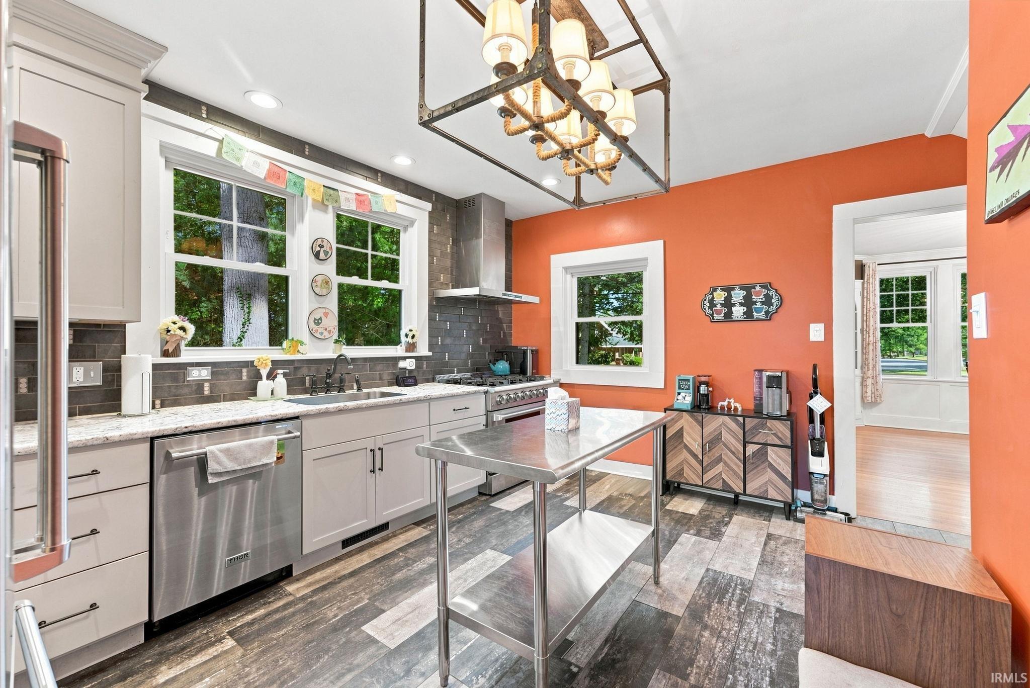 Kitchen featuring wood-finish flooring, light grey cabinetry, stainless steel appliances, and a grey tile backsplash