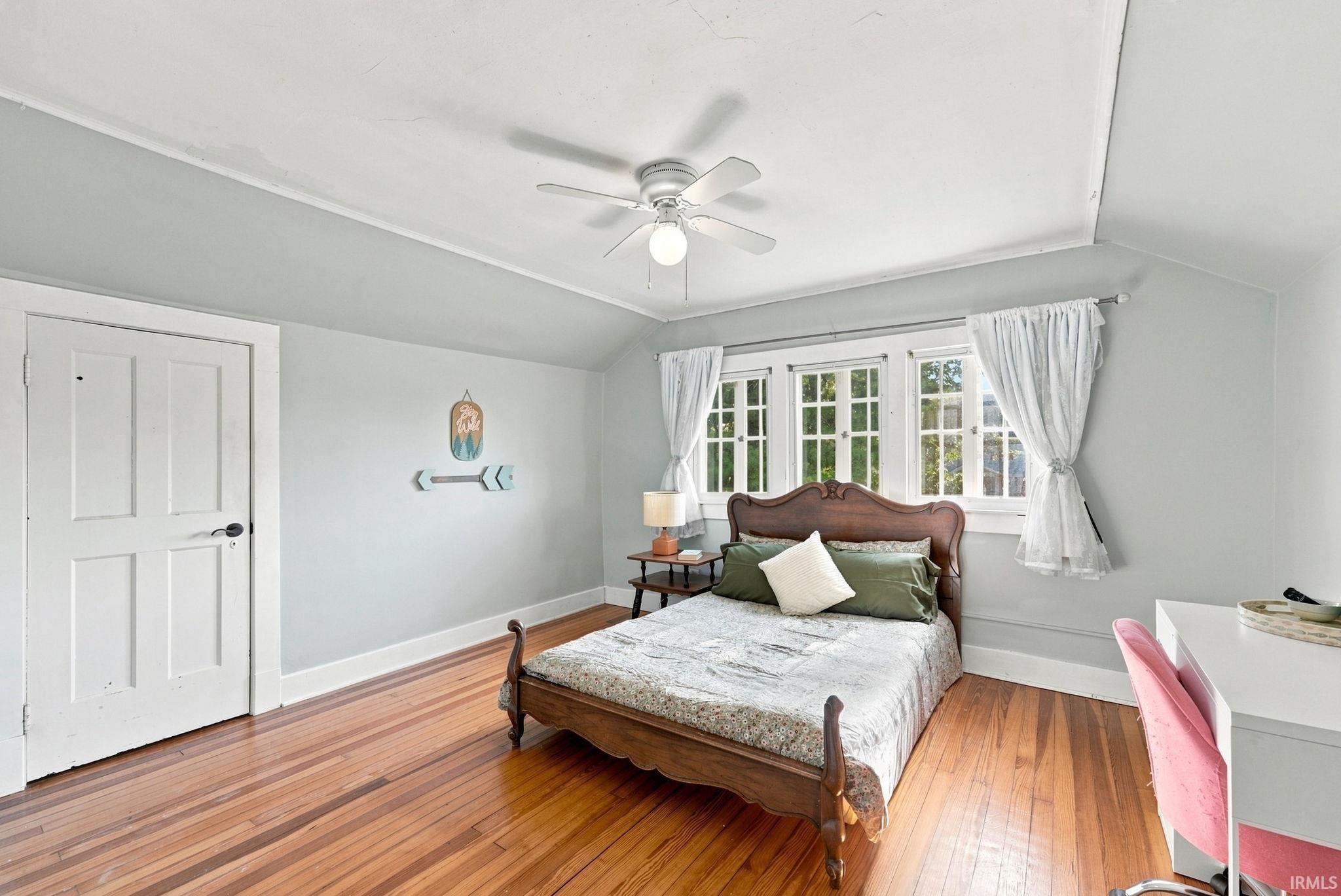 Room featuring wood-finish flooring, a multi-pane window, and a ceiling fan with integrated lighting