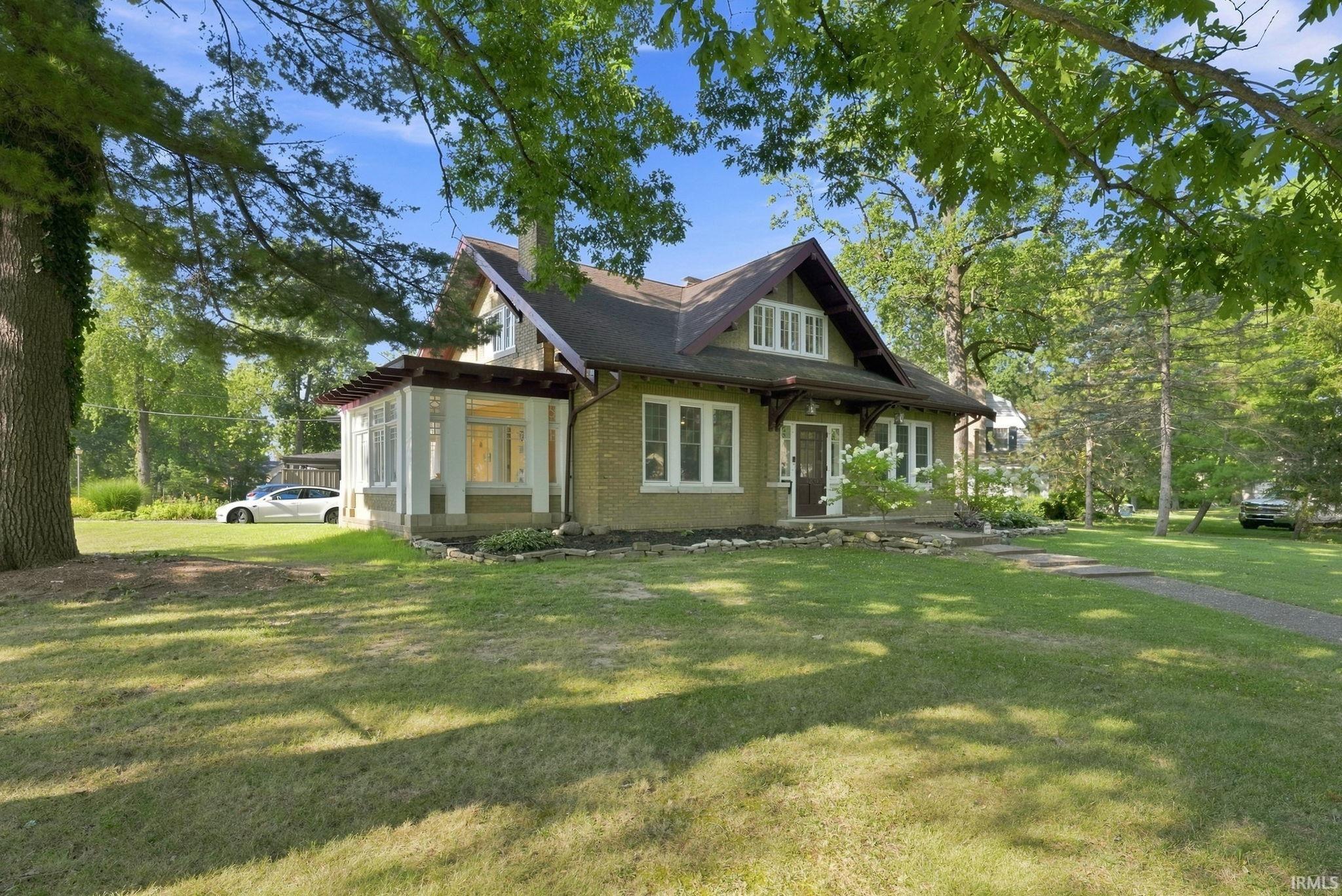 Craftsman-style residence featuring a prominent gabled roofline, light-colored brick facade, and white-trimmed windows