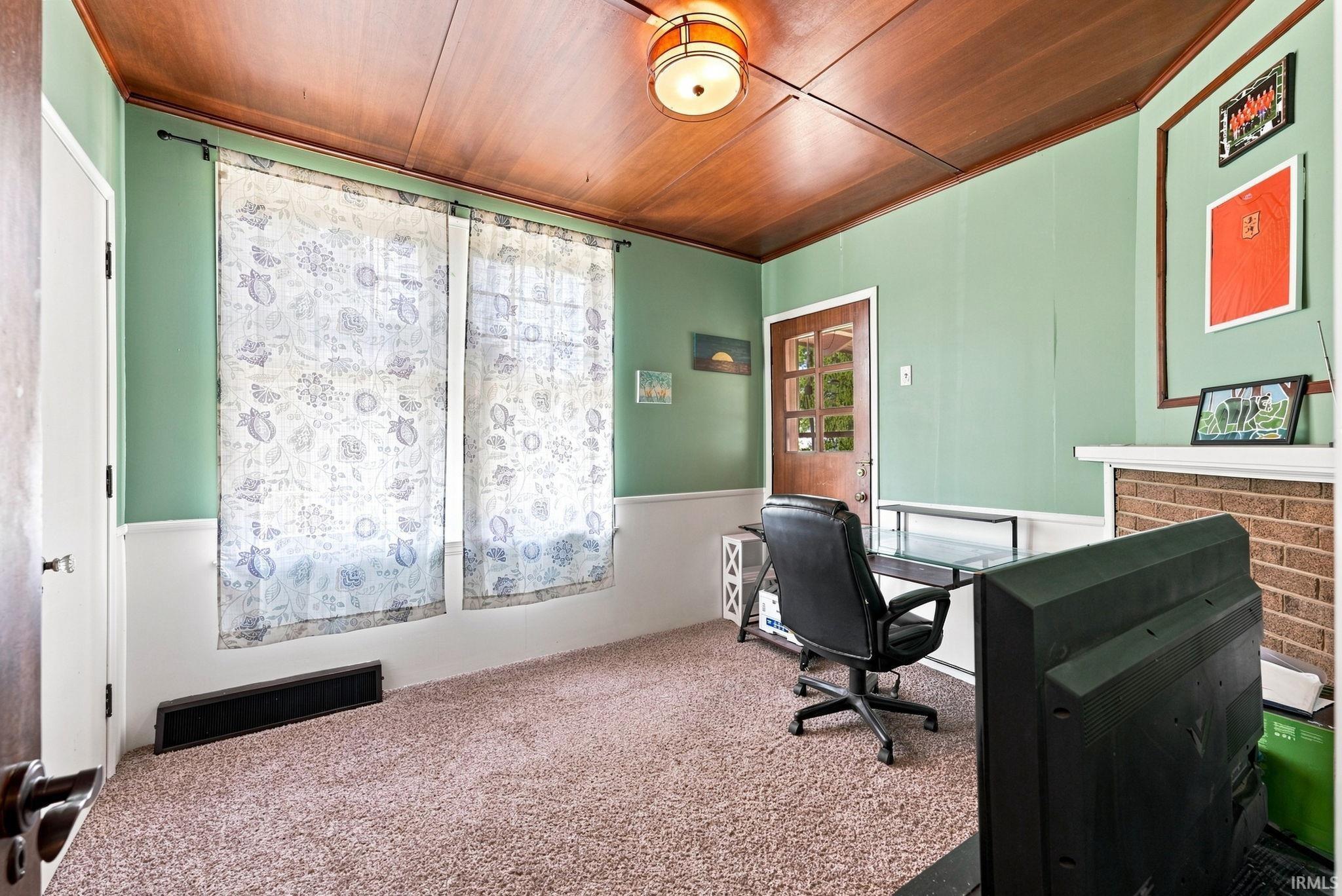 Carpeted interior space featuring a wood-panel ceiling and a wood-frame door with glass inserts