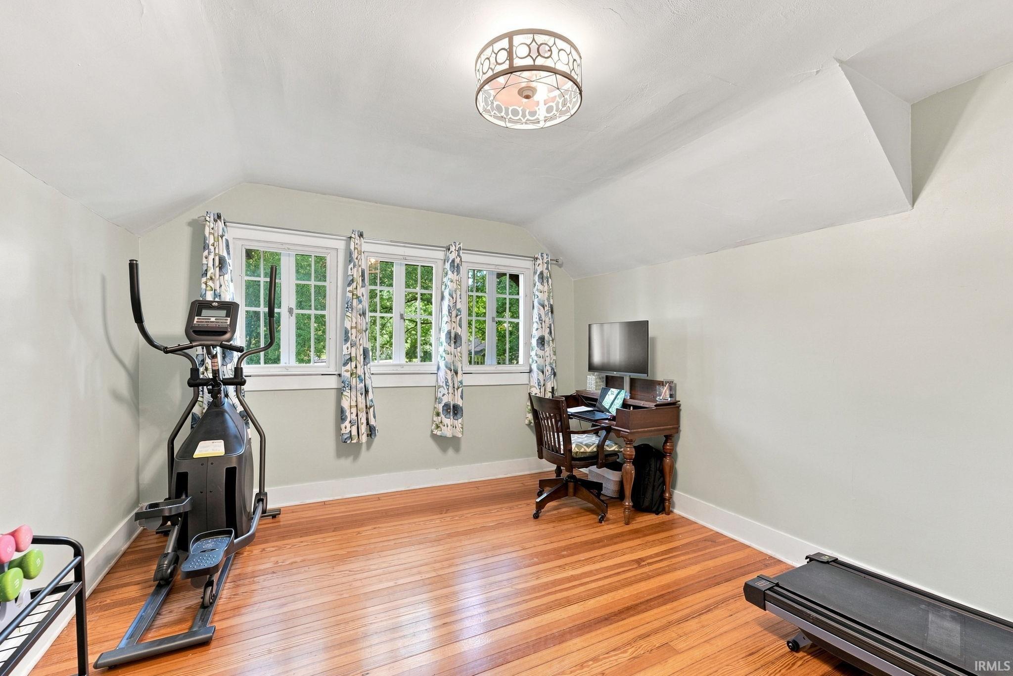 Room featuring hardwood flooring, white baseboards, and light-toned walls