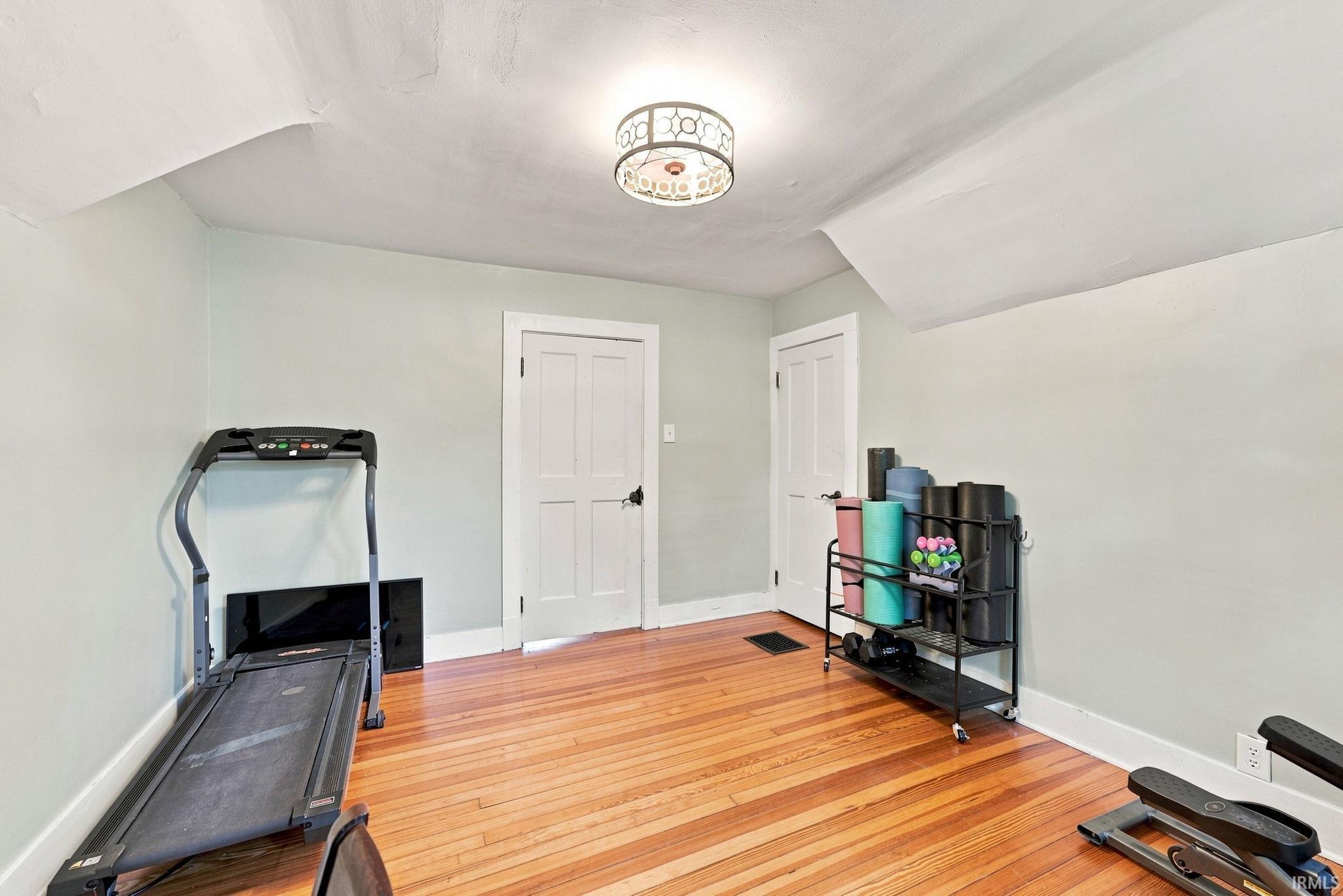 Hardwood flooring room with two panel doors and a decorative flush mount ceiling light fixture