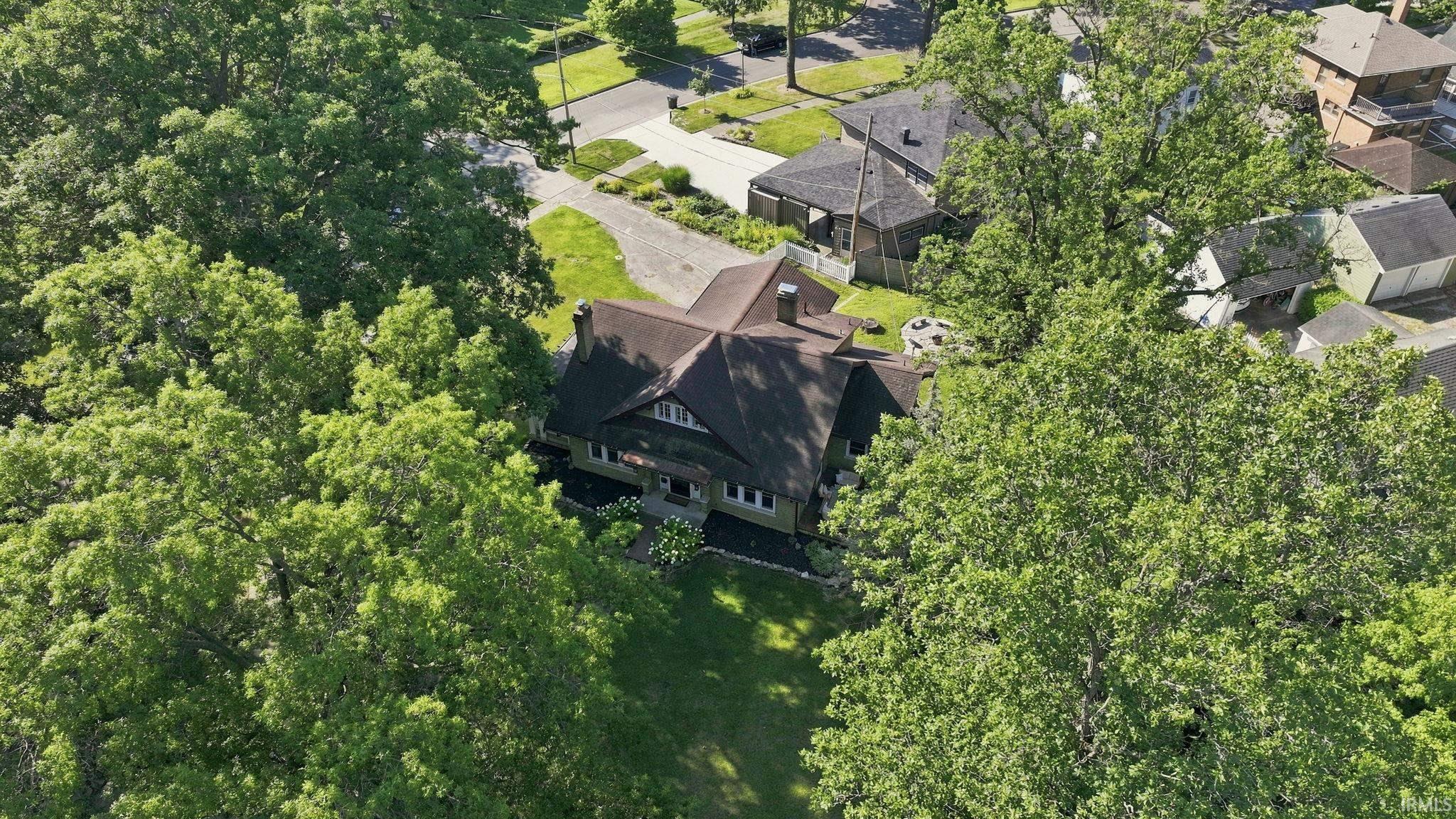 Tudor Revival residence featuring a stone and stucco façade, multi-gabled roofline, mature trees, and a paved driveway