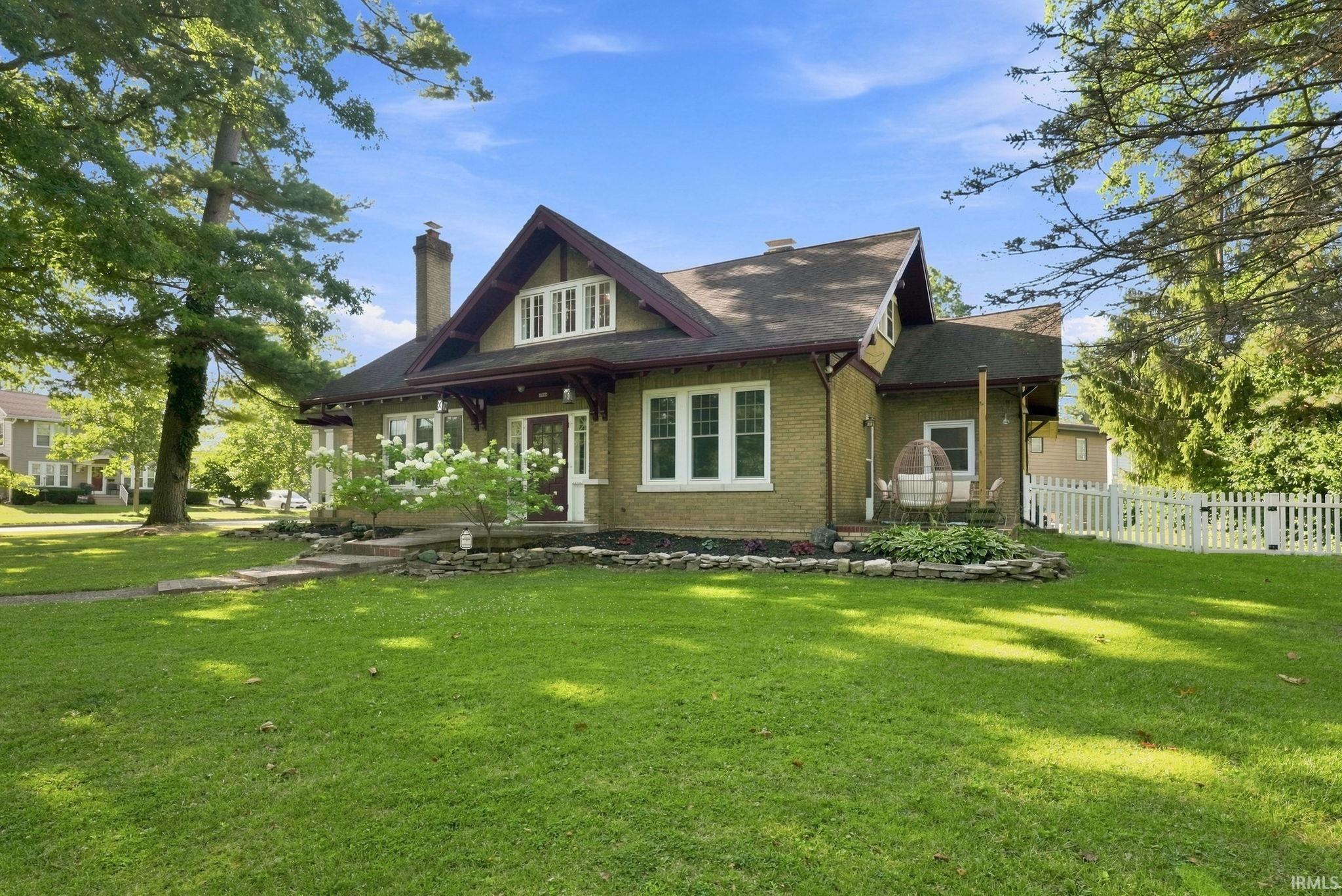 Craftsman-style residence featuring a brick facade, white window trim, and a prominent front gable with decorative detailing