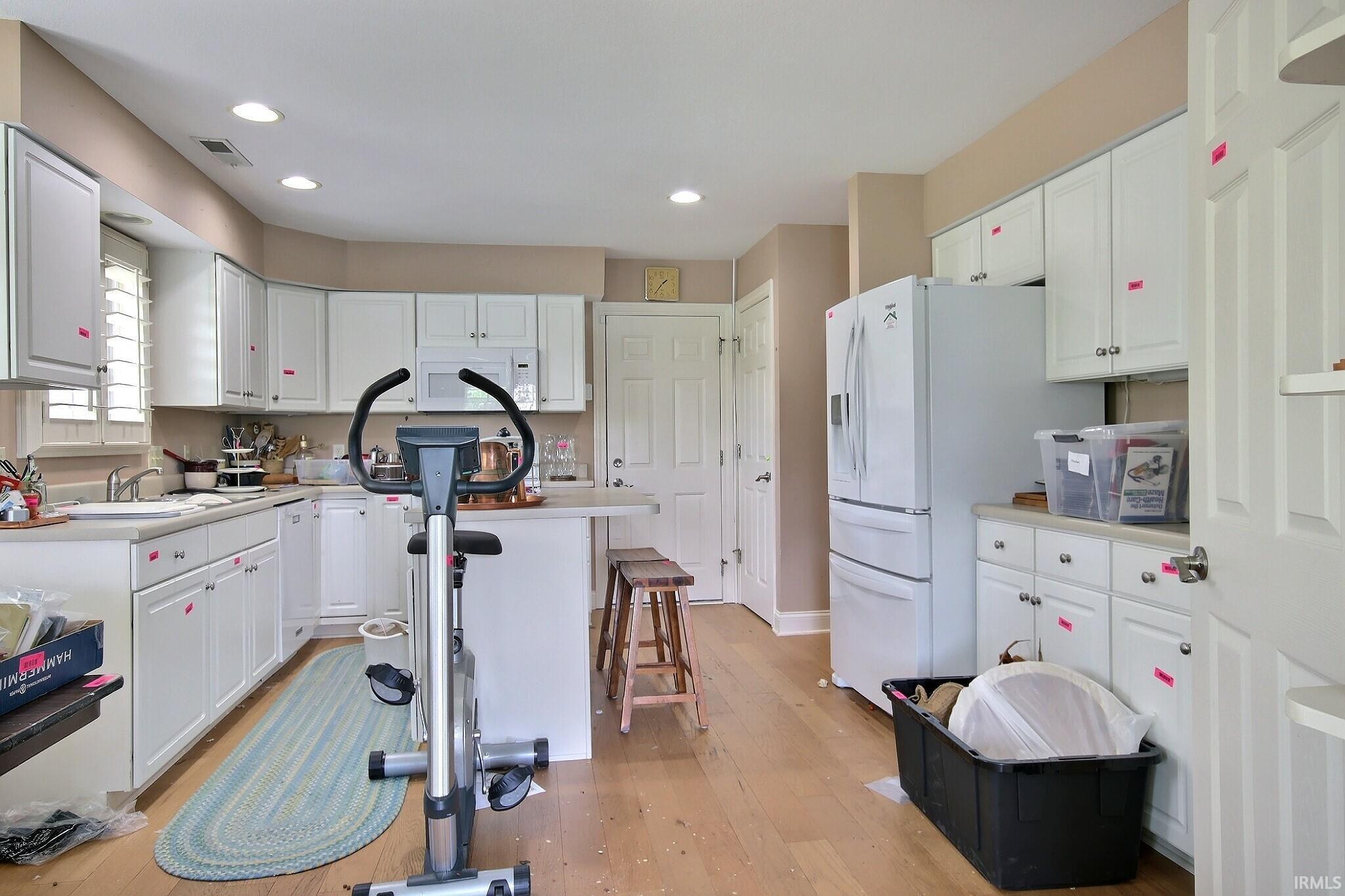 Kitchen featuring white cabinetry, light-tone flooring, recessed lighting, and a kitchen island with seating