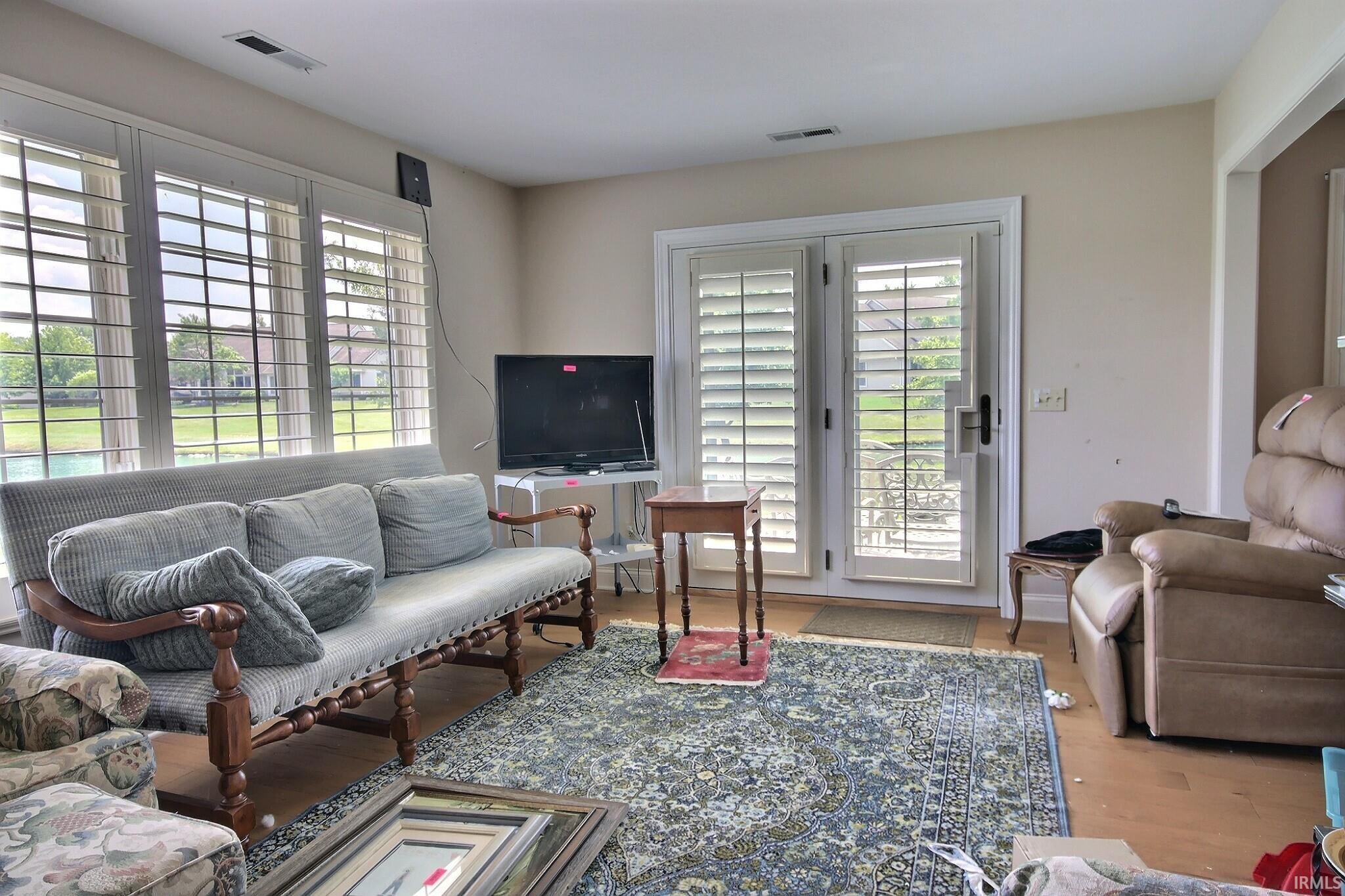 Living area featuring light wood-finish flooring, neutral wall tones, and a patterned area rug