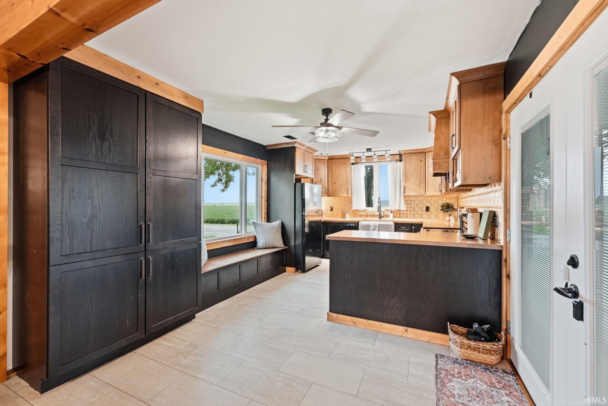 Kitchen featuring dark wood-finish cabinetry, light wood-finish upper cabinetry, light-toned tile flooring, built-in window seating, and a ceiling fan