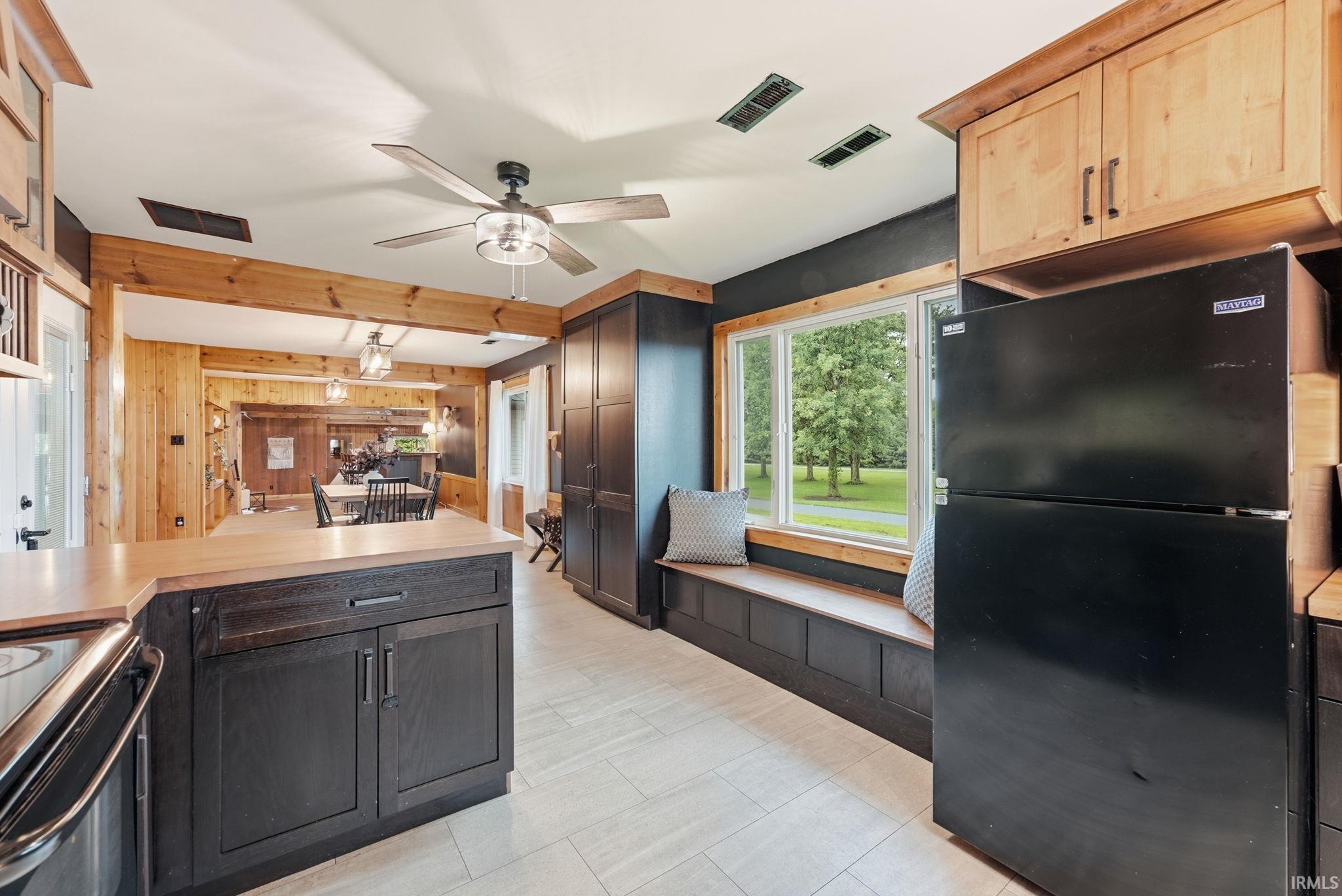Kitchen with wood-finish flooring, dark cabinetry, and light wood countertops