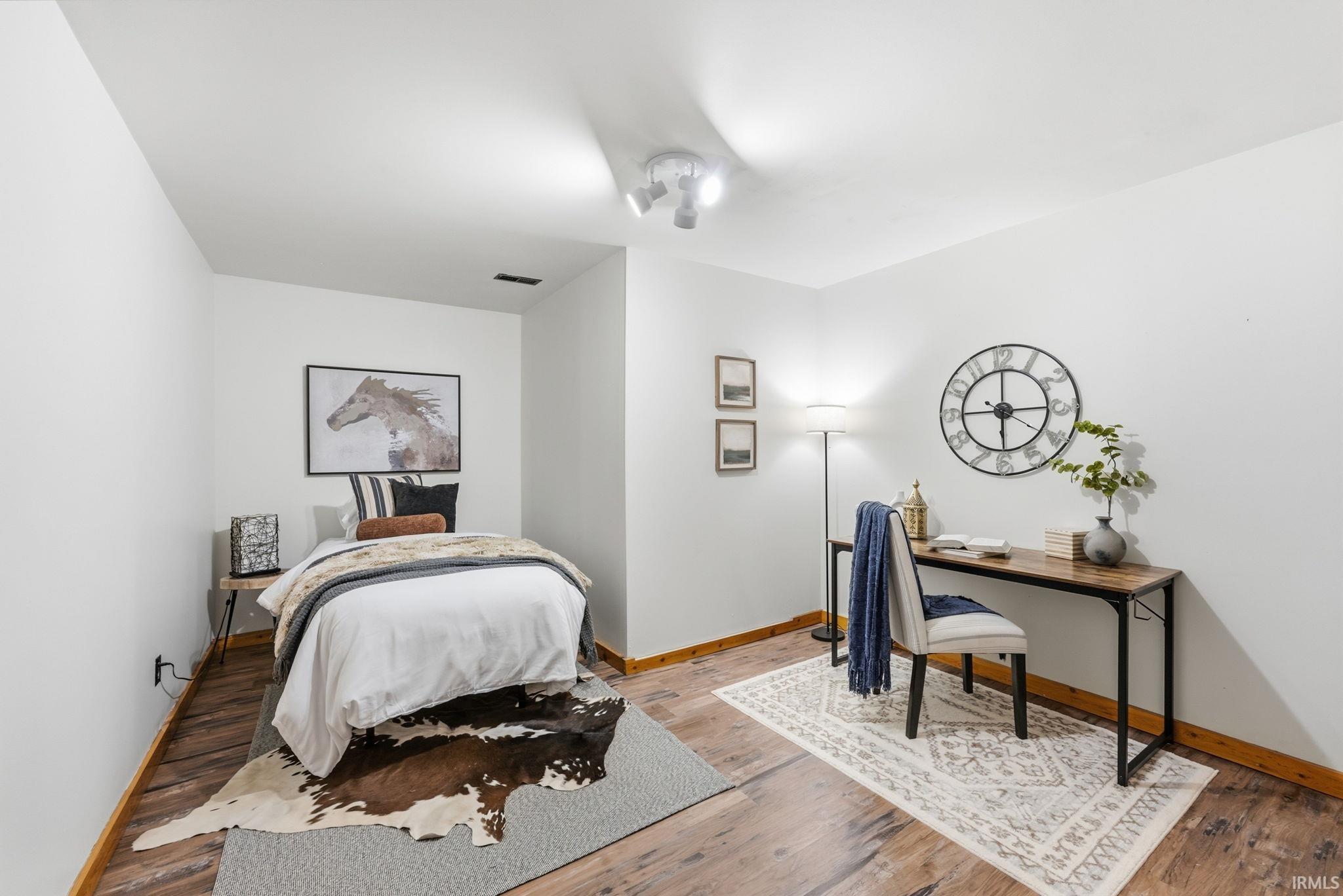 Wood-finish flooring, white walls, and track lighting fixtures