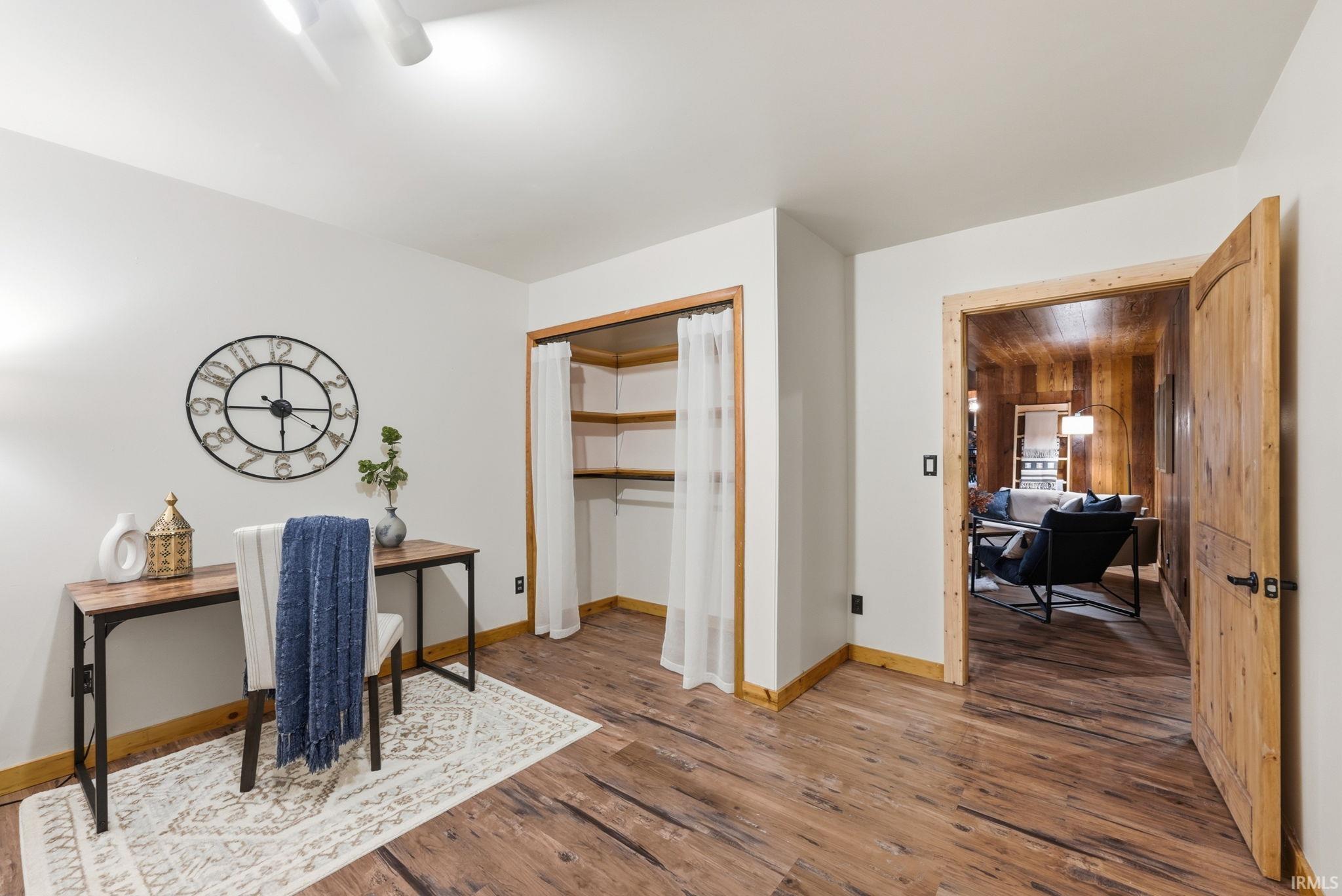 Wood-finish flooring throughout, with a built-in closet featuring shelving and curtain closure