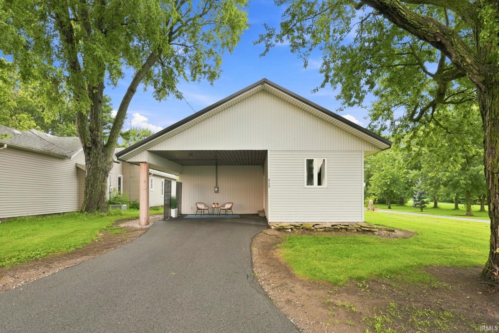 White siding exterior with a dark roof and a covered carport entrance