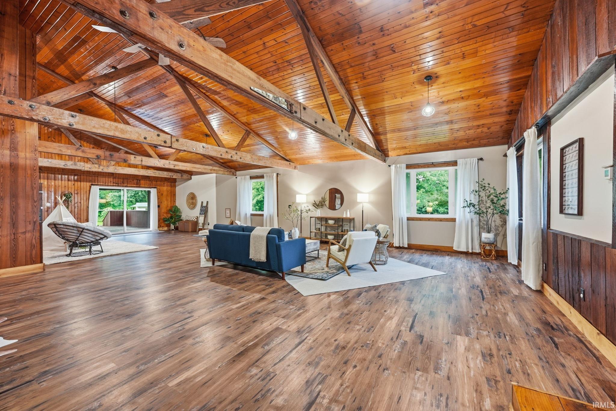Vaulted wood-paneled ceiling with exposed beams, wood-finish flooring, sliding glass doors, and multiple windows