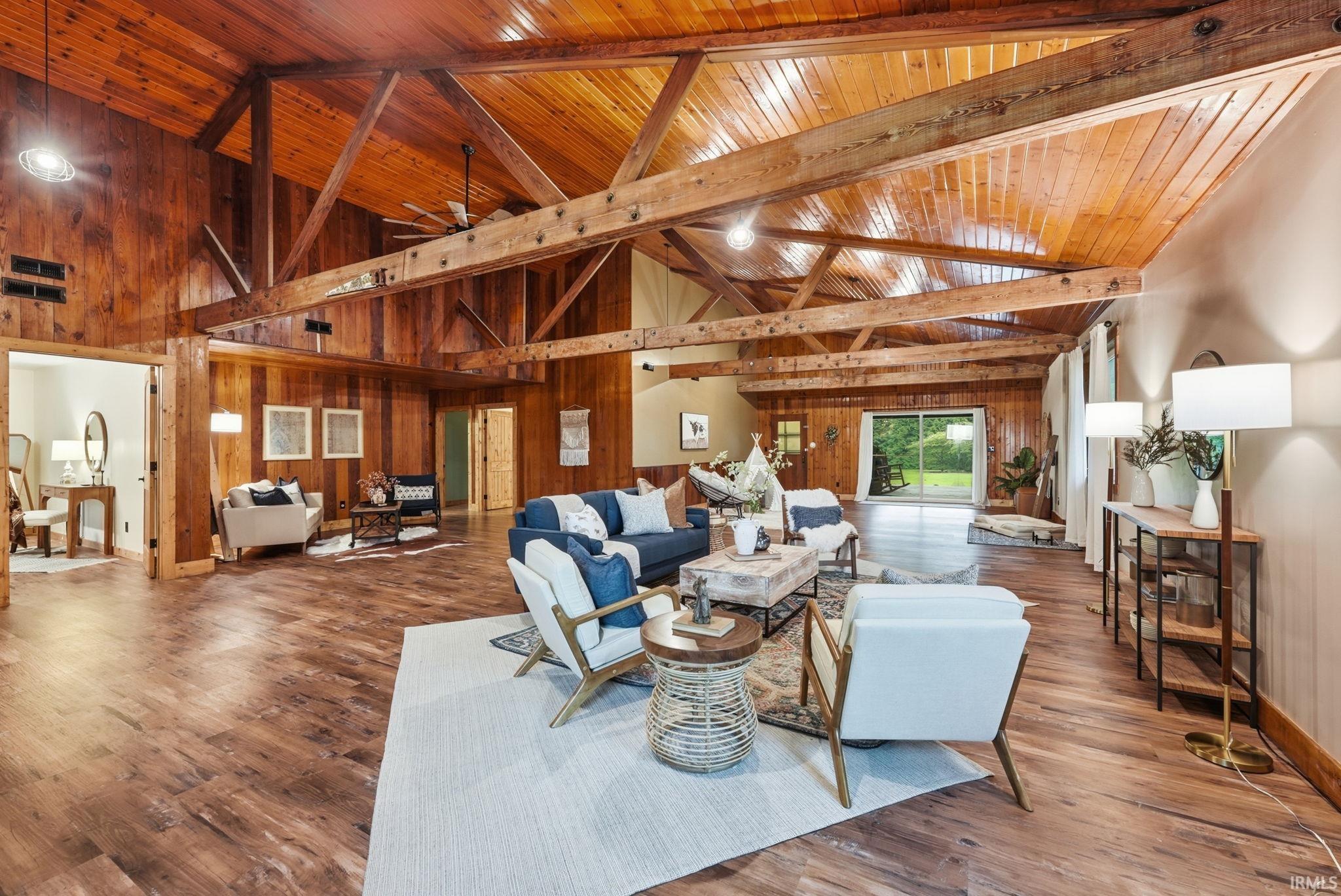 Vaulted wood-paneled ceilings with exposed beams, wood-finish flooring, and sliding glass doors to the exterior