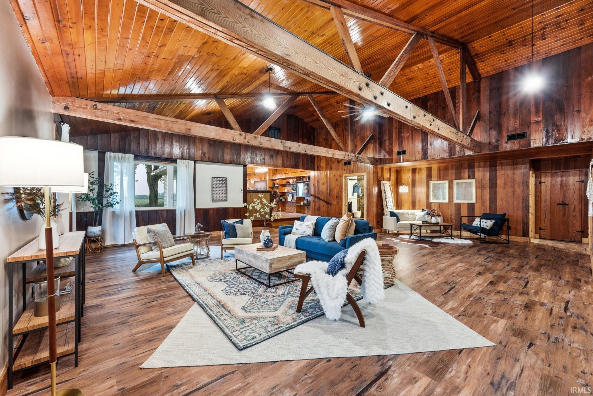 Vaulted wood-paneled ceiling with exposed beams, wood-finish flooring, wood-paneled walls, and multiple windows