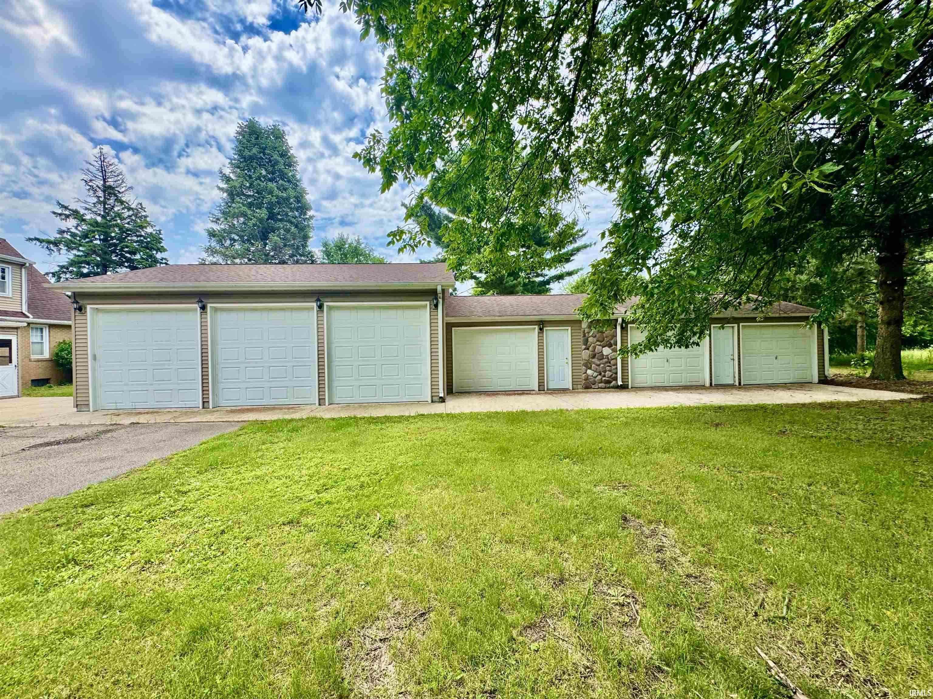 Extensive garage structure featuring six individual bays with white paneled garage doors, a stone facade accent, and two entry doors
