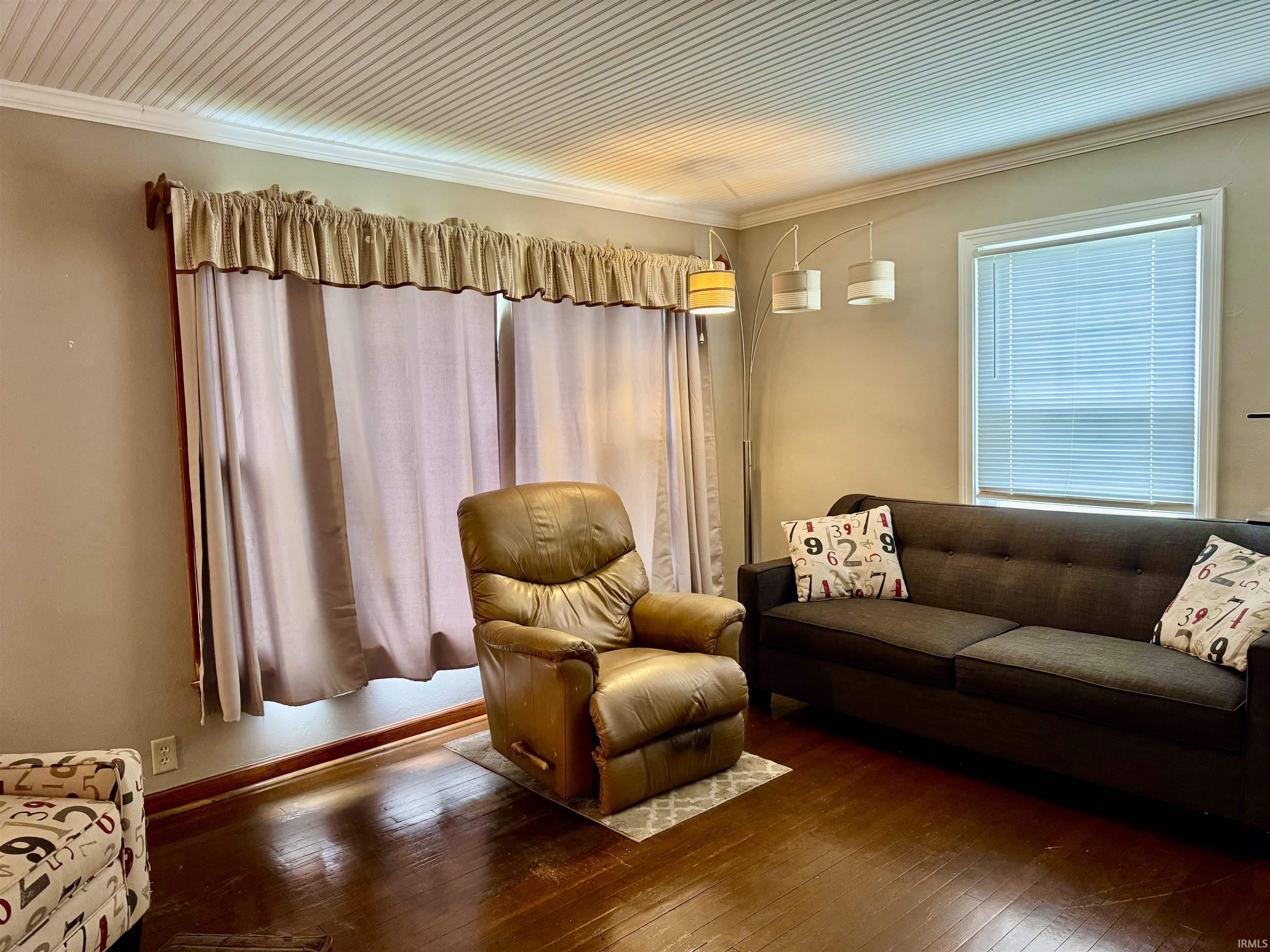 Living area featuring dark wood-finish flooring, a beadboard ceiling, and crown molding