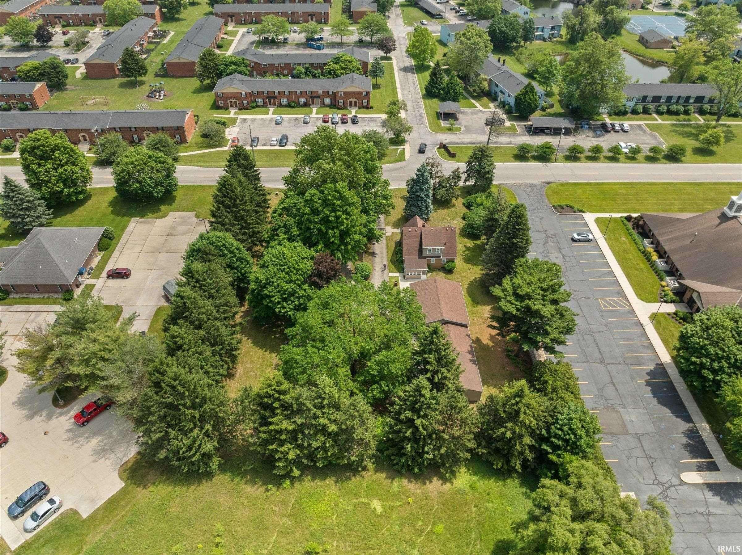 Aerial property view featuring mature trees and a residential structure with a brown shingle roof
