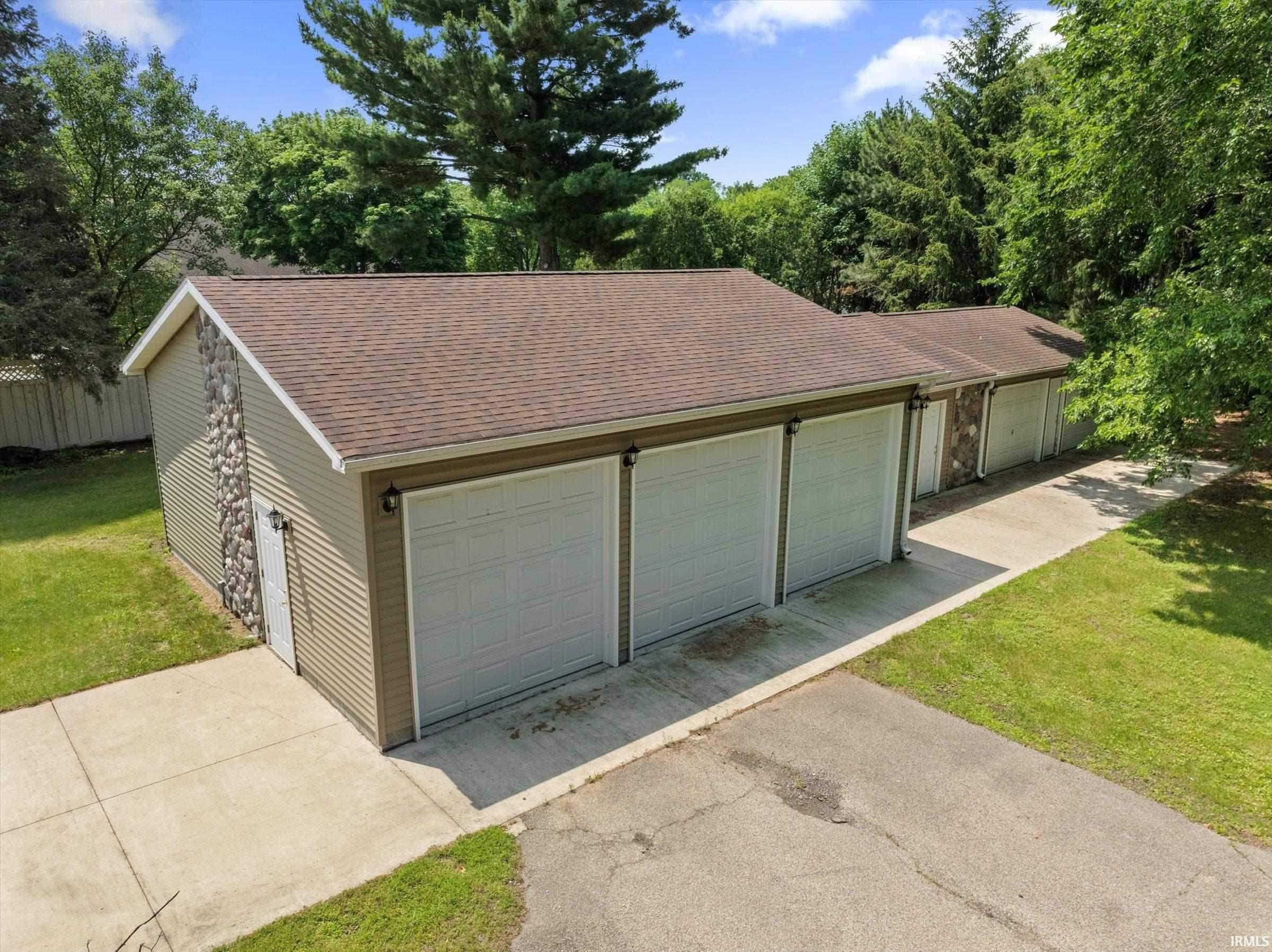 Five bay garage structure with asphalt shingle roofing and beige horizontal siding