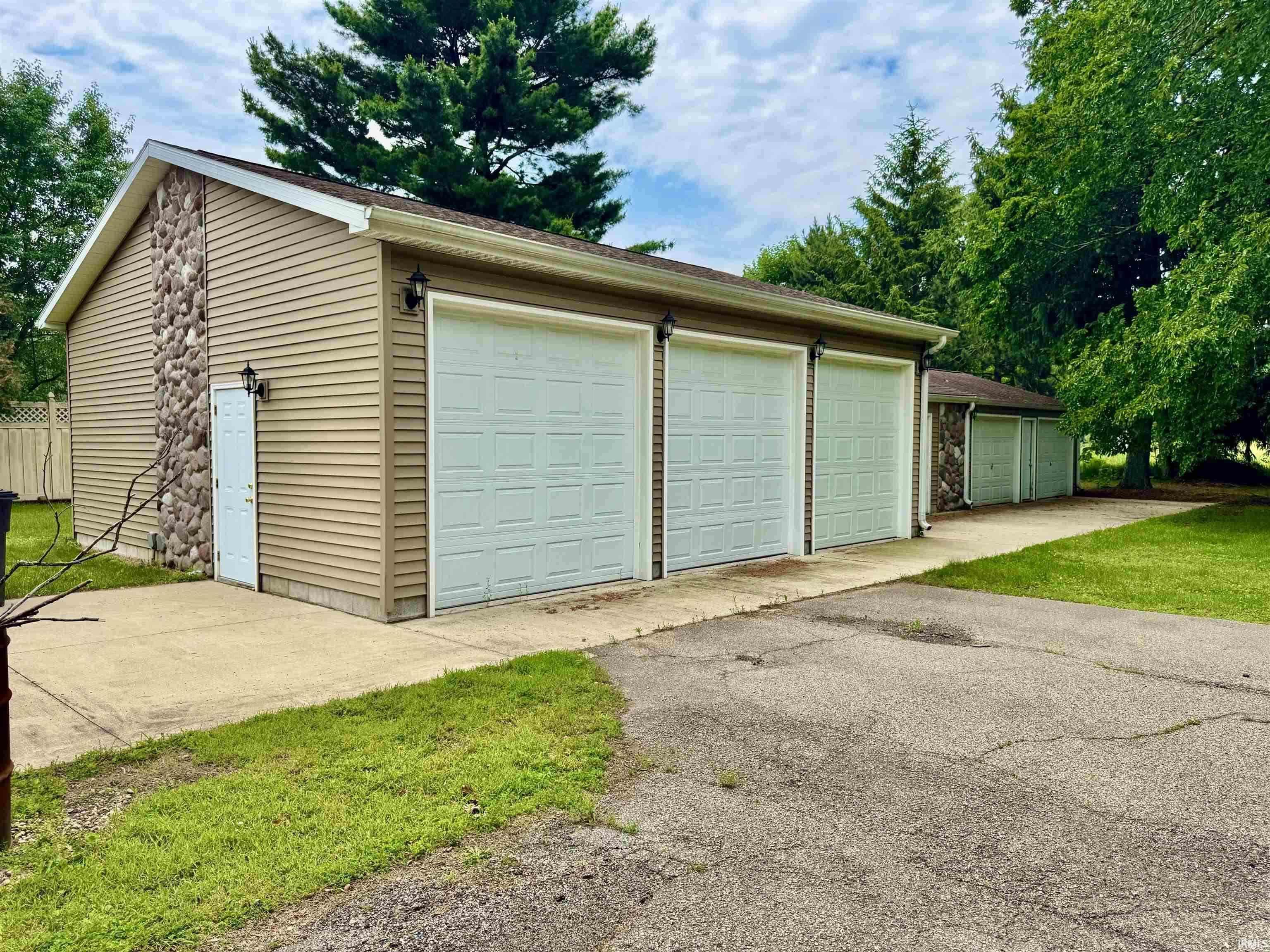 Detached garage structure featuring light brown siding and stone veneer accents