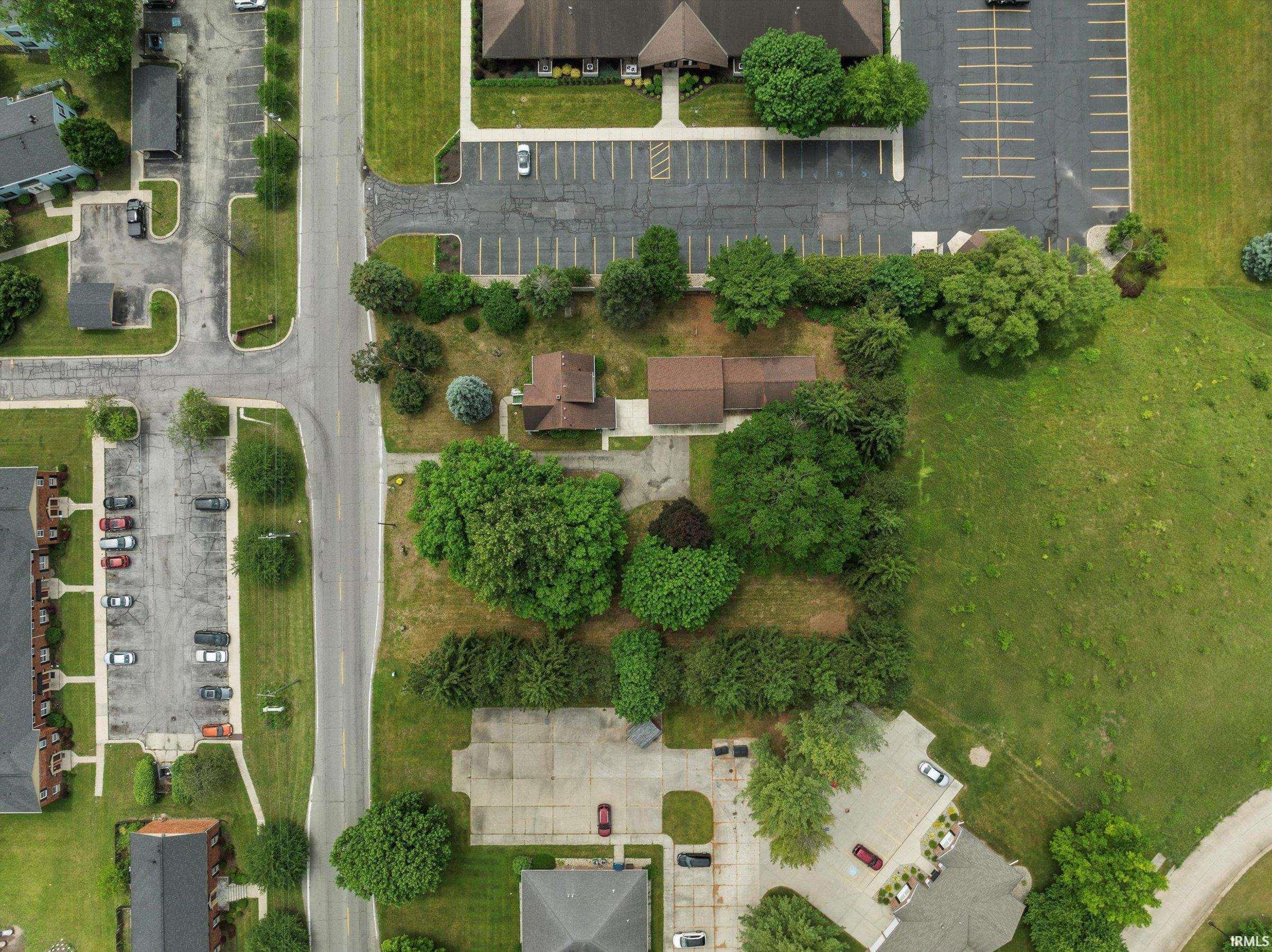 Residential property featuring two structures, mature trees, and a substantial undeveloped grass area