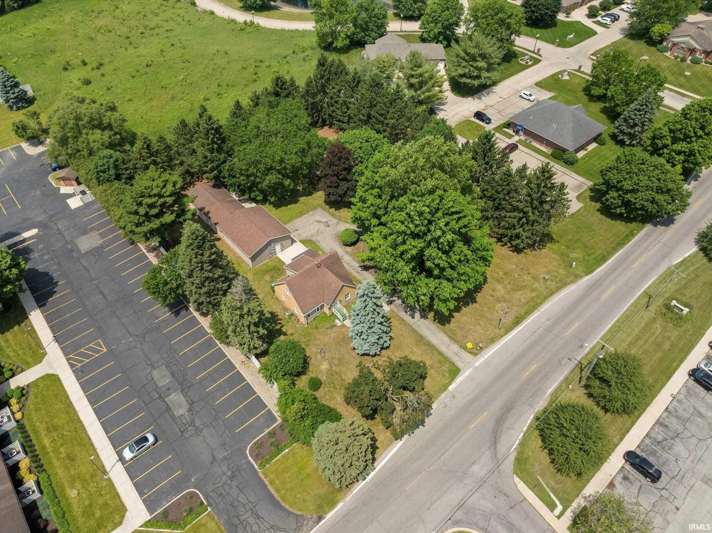 Aerial perspective showcasing a parcel with two structures, mature trees, and landscaping