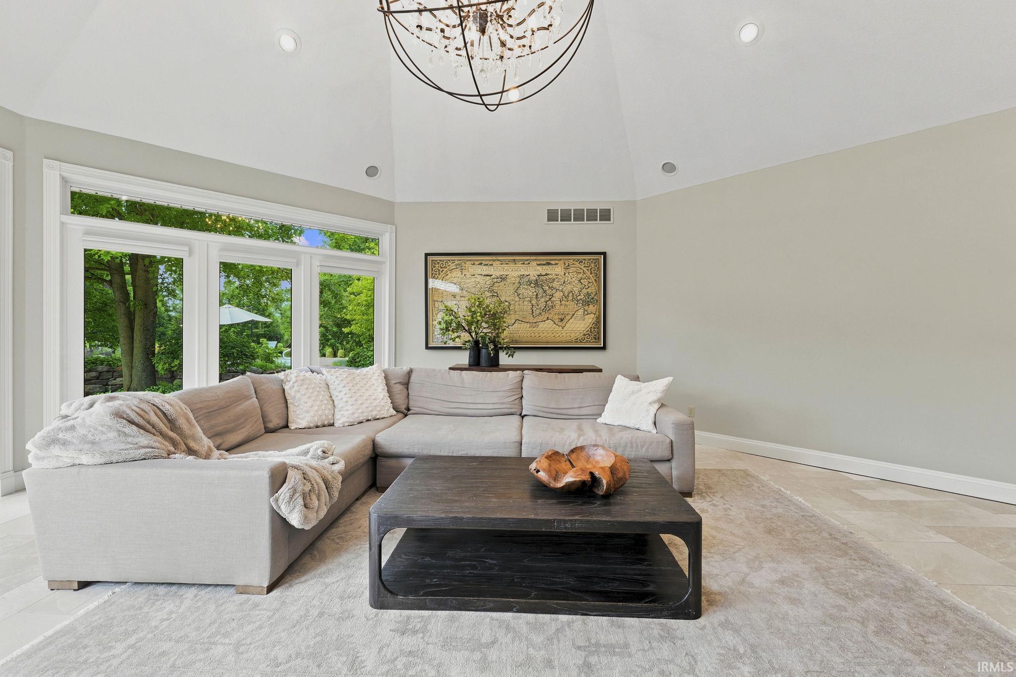 Vaulted great room featuring heated floors, abundant natural light, courtyard views, and a stunning fireplace.