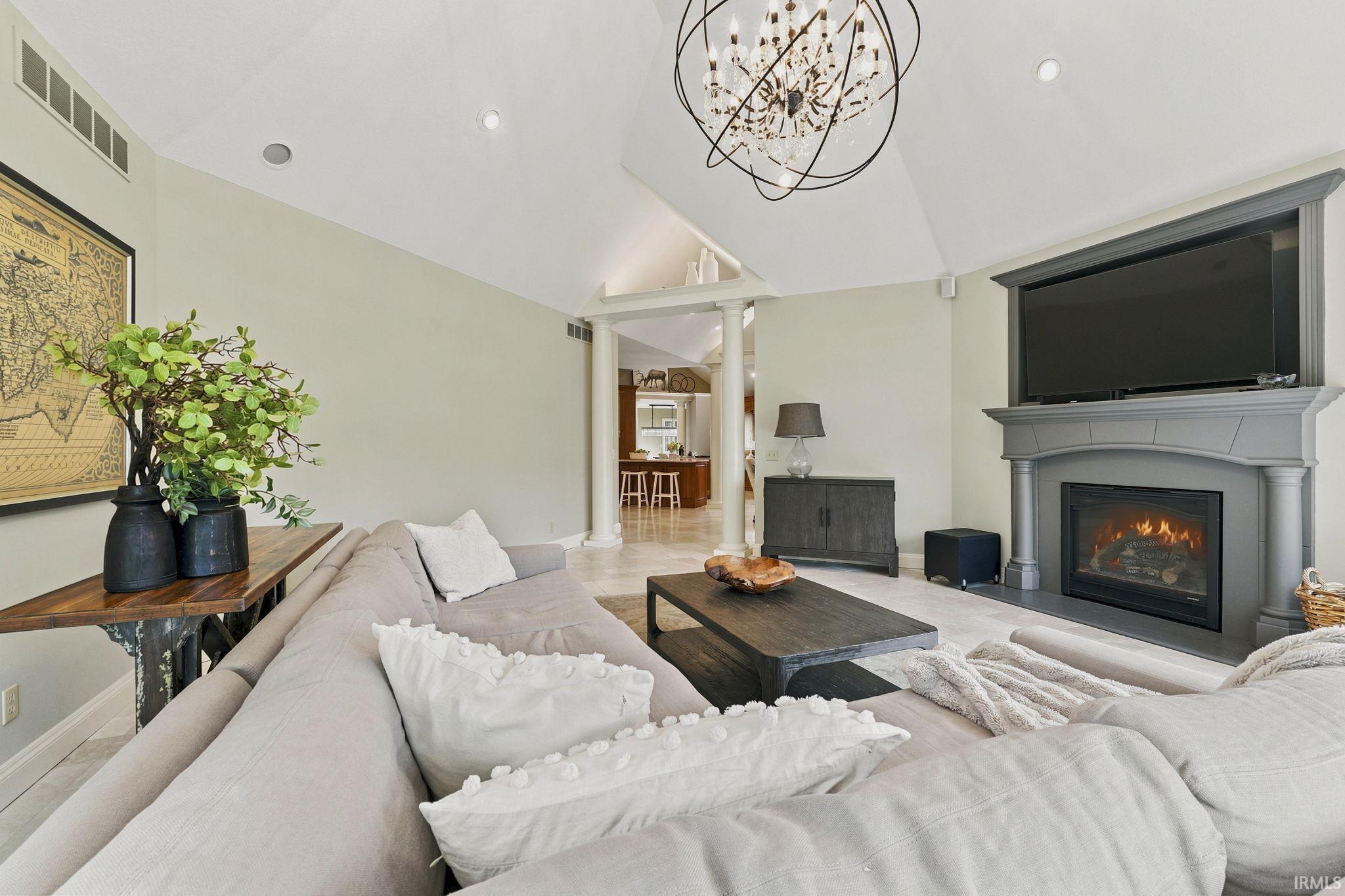 Vaulted great room featuring heated floors, abundant natural light, courtyard views, and a stunning fireplace.