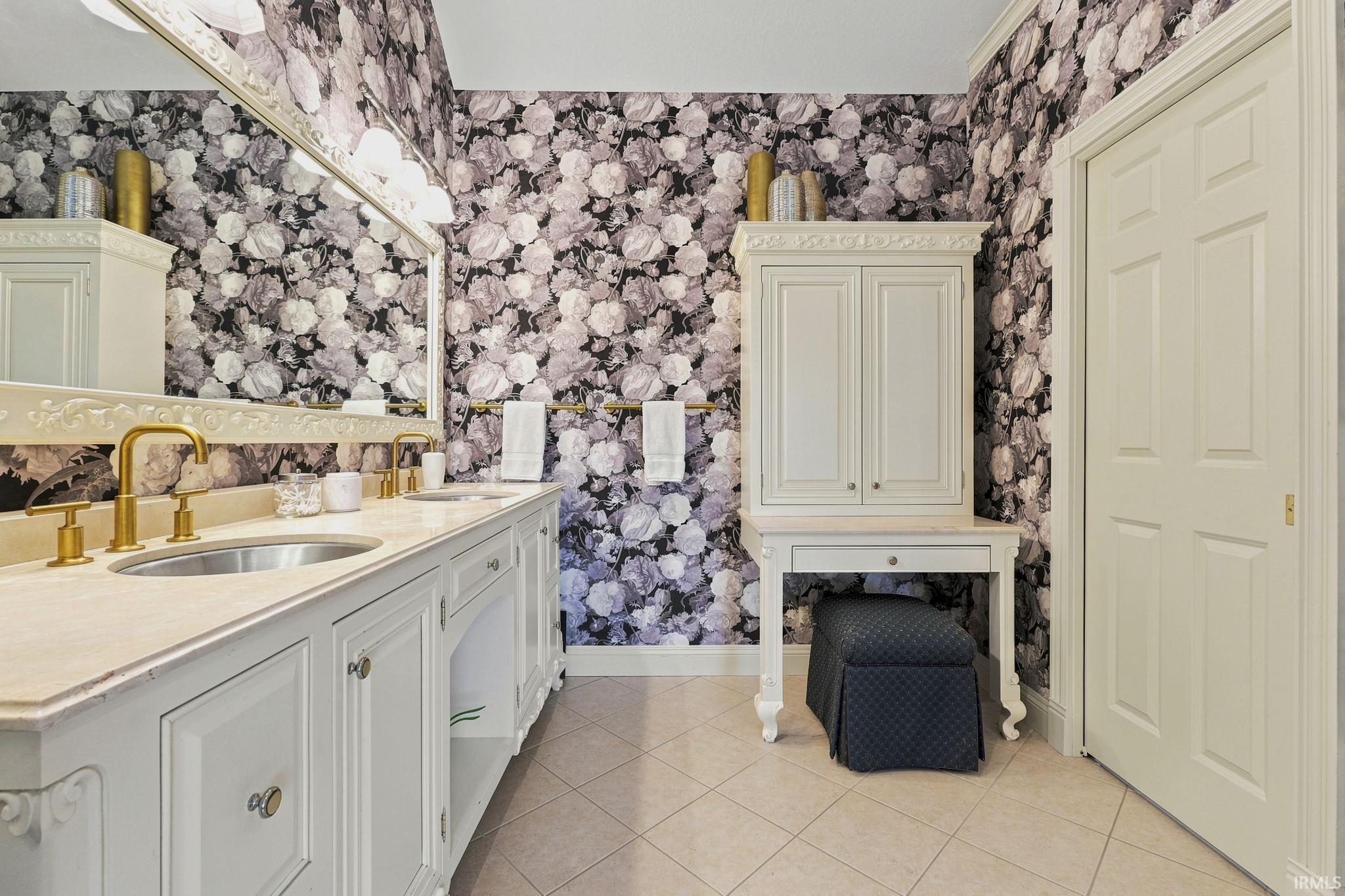 Luxurious primary bath featuring dual vanities, furniture-style custom cabinetry, glass block walk-in shower, and soaking tub with pond views and fireplace.