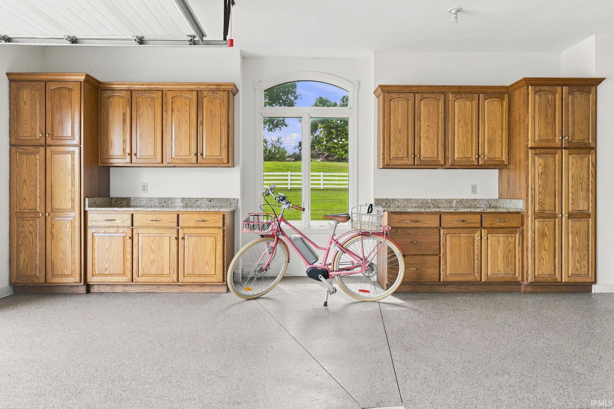 Heated three-car garage featuring epoxy flooring, custom cabinetry with granite countertops, and exceptional storage.