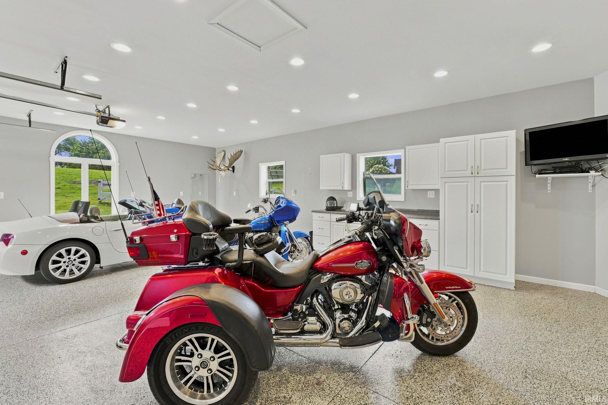 Versatile heated and cooled workshop offering three additional vehicle bays, epoxy flooring, and a custom-built work area.