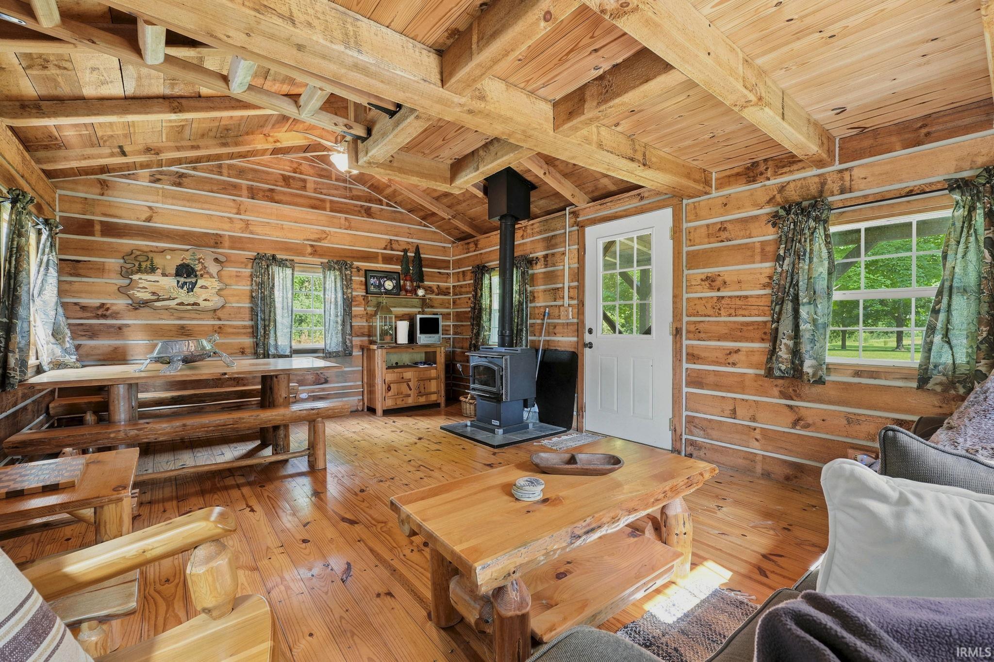 Charming log cabin interior featuring a wood-burning stove, electricity, and a cozy loft sleeping area-an inviting retreat to relax and unwind.