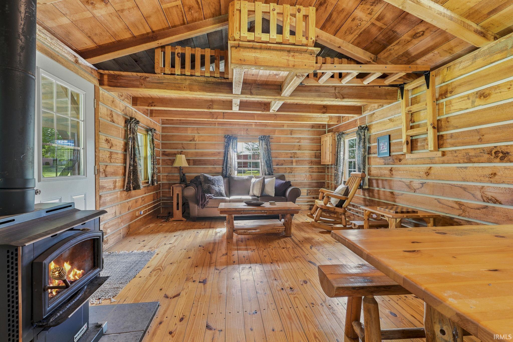 Charming log cabin interior featuring a wood-burning stove, electricity, and a cozy loft sleeping area-an inviting retreat to relax and unwind.