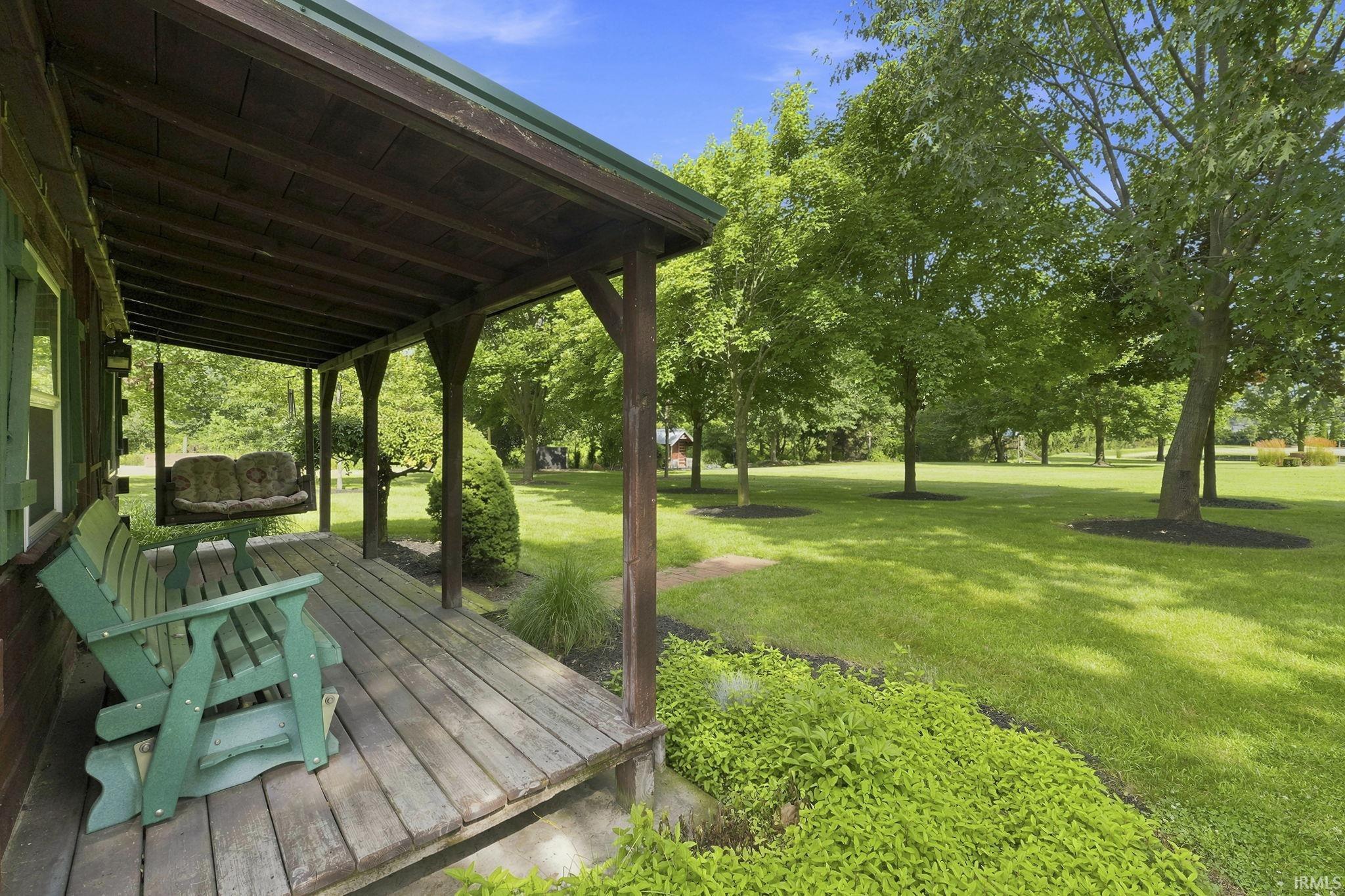 Covered cabin porch featuring a charming bench swing and peaceful views of the surrounding landscape.