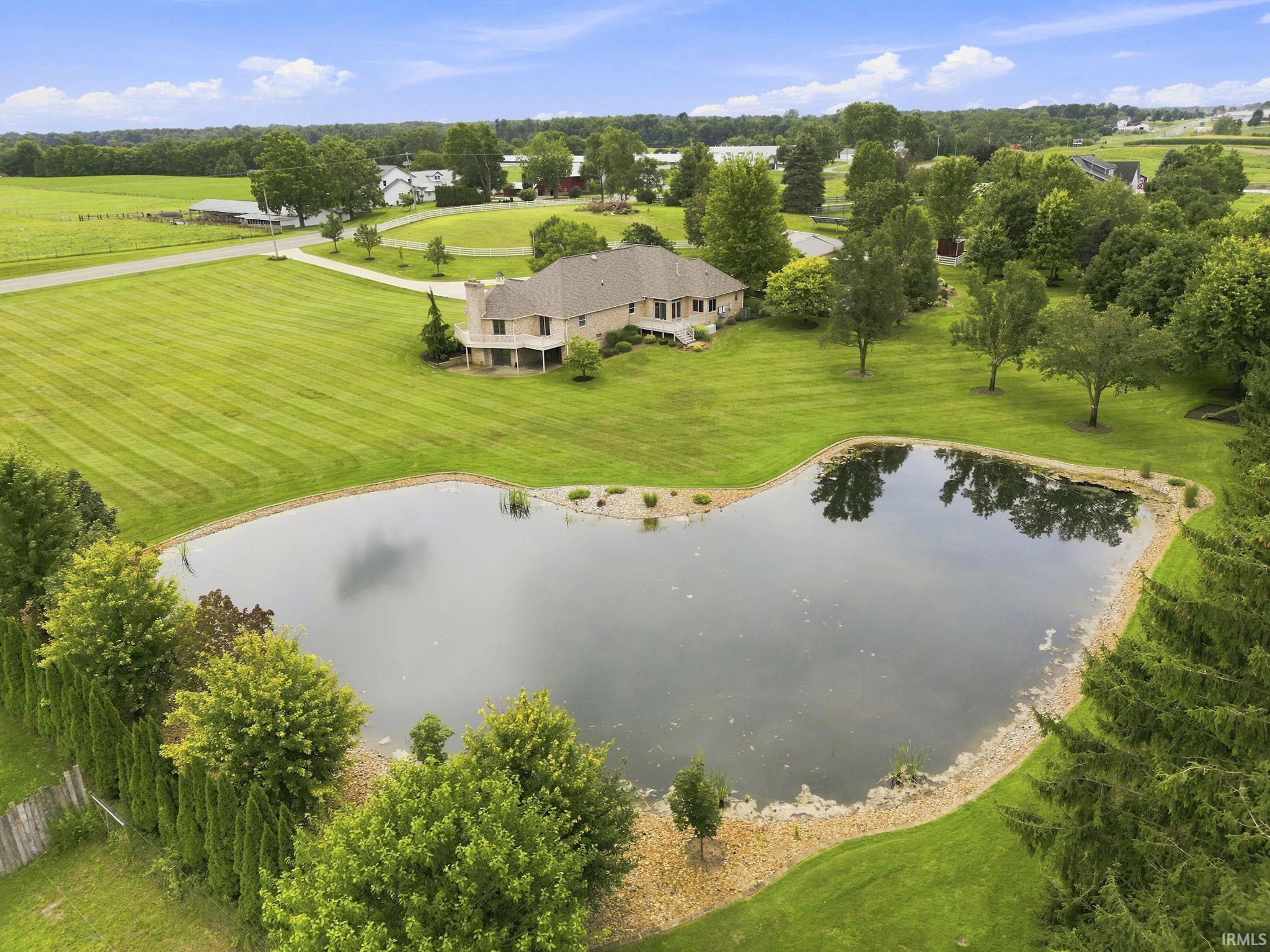 Aerial views of the private stocked pond featuring a recently added rock border for easy maintenance, a sandy shallow area, and deeper waters stocked with bass and bluegill.