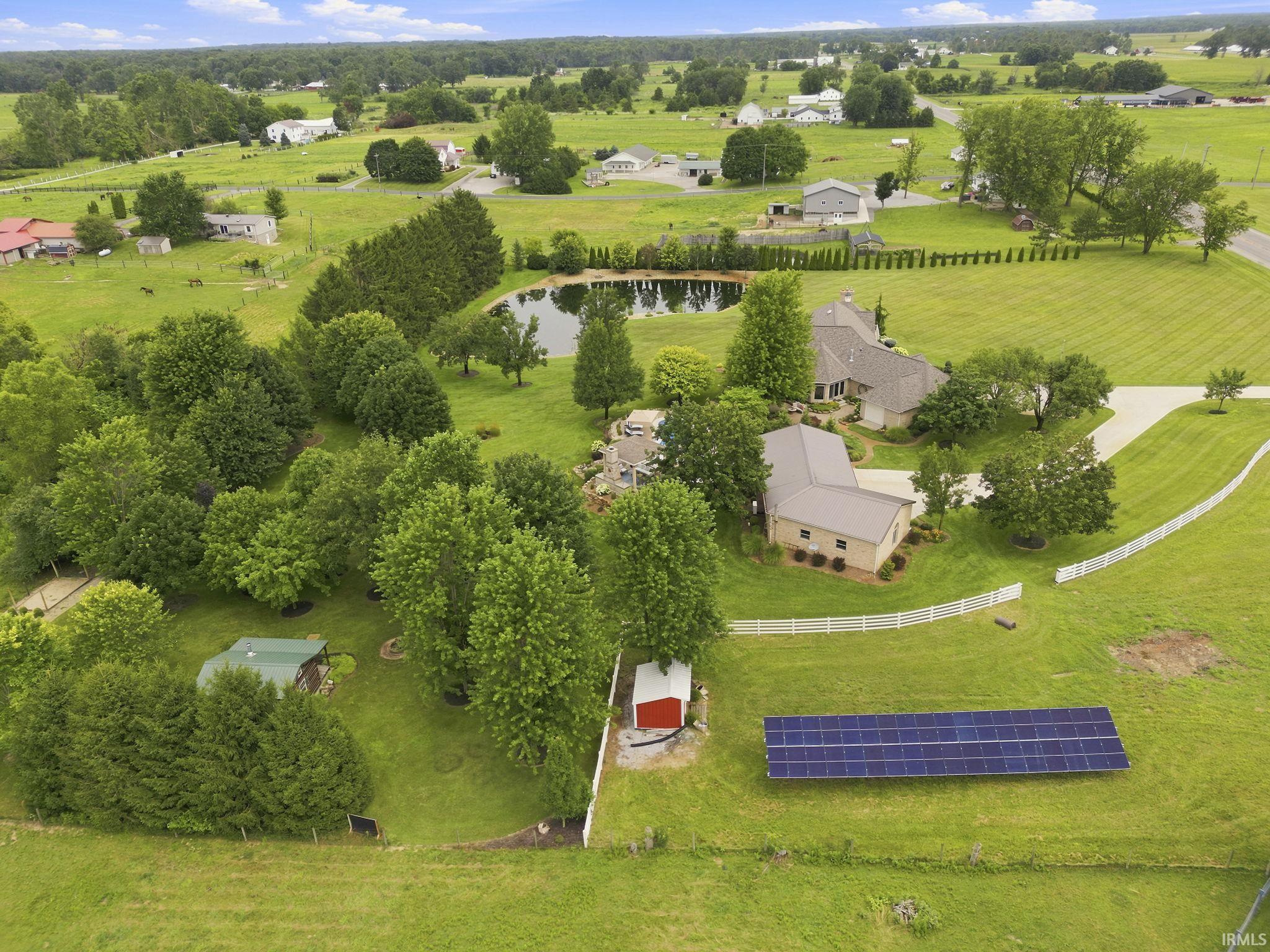 Aerial perspective showcasing the expansive estate, solar power system, and fenced pasture area offering endless possibilities for animals, recreation, or enjoying the natural beauty of the property.
