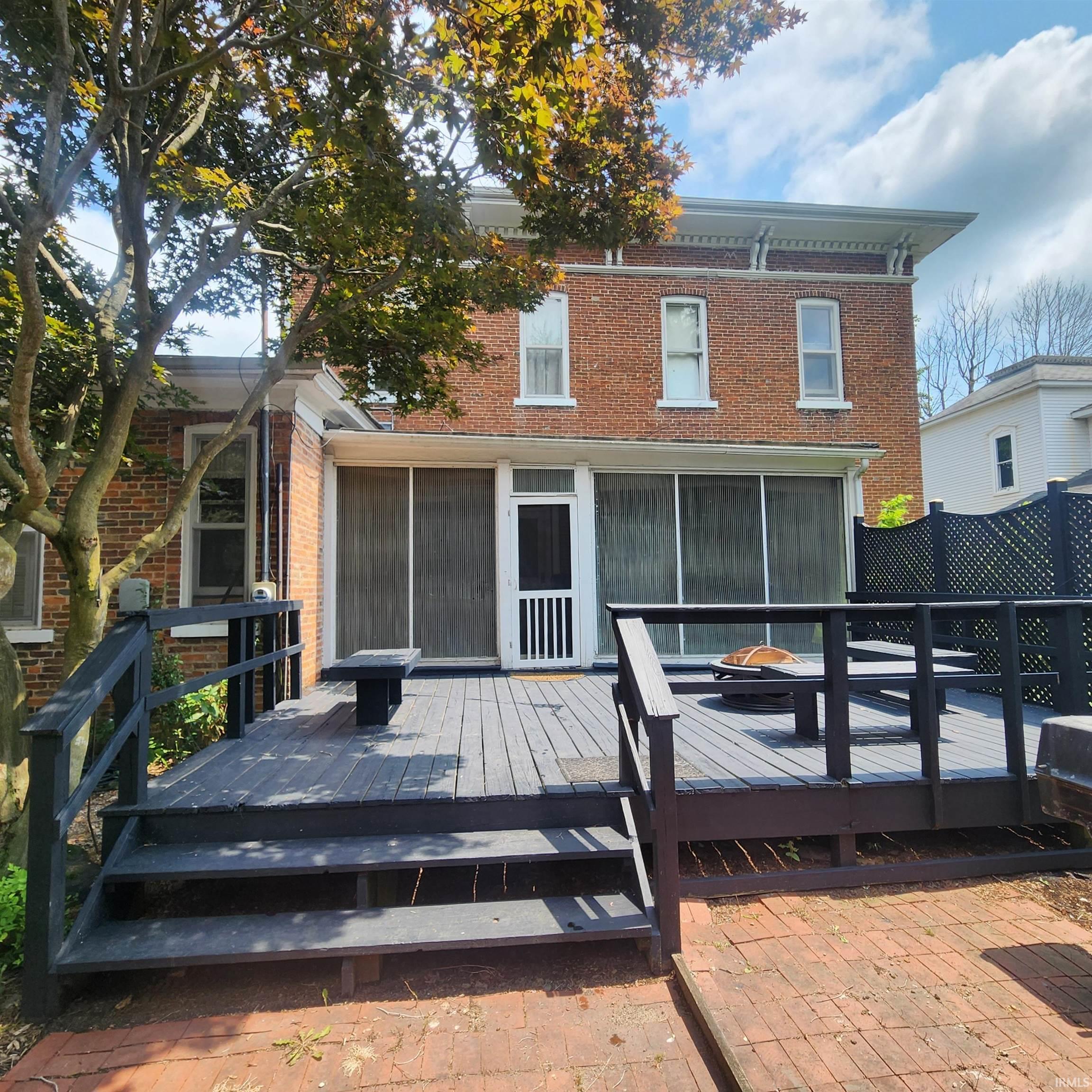 Expansive wood deck with dark-stained railings and steps, leading to a screened porch entry