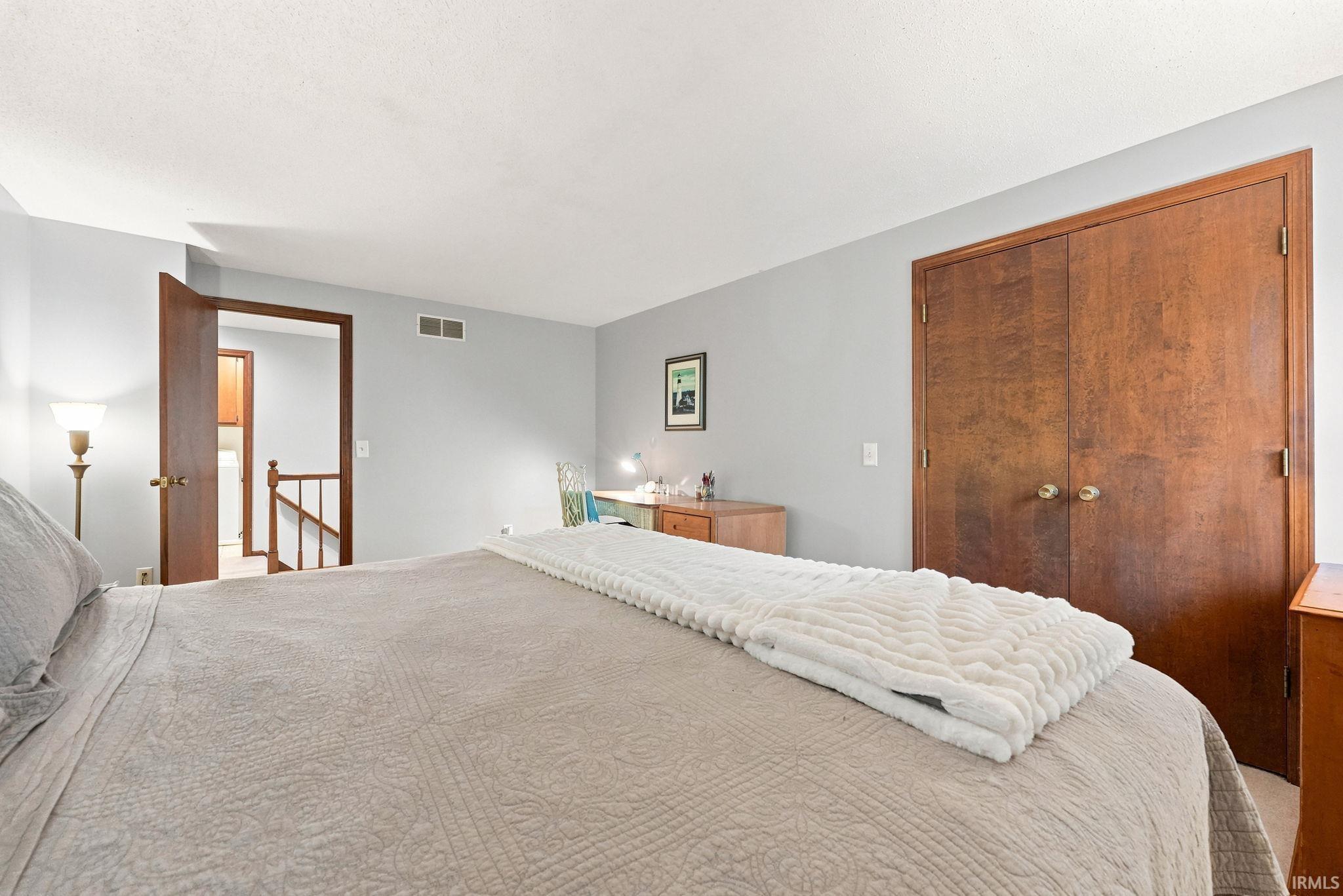 Spacious room featuring light gray walls, wood-finish bi-fold closet doors, and wood-finish trim