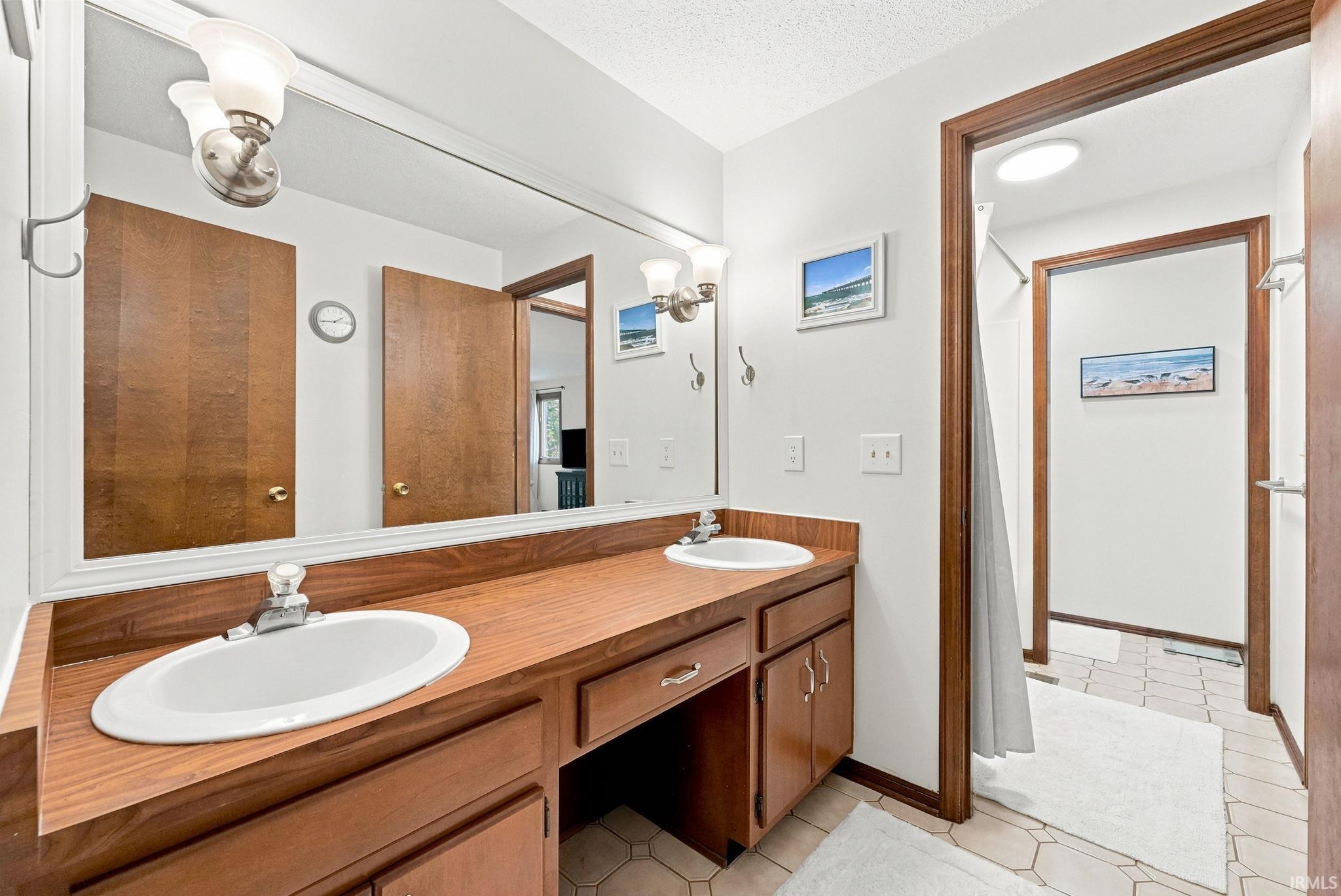 Bathroom featuring a double vanity with wood-finish countertop, integrated sinks, and lower cabinetry
