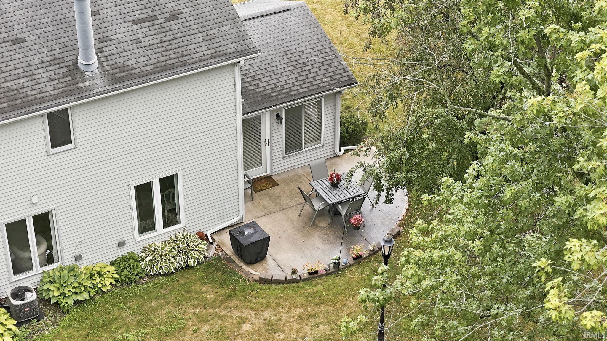 Concrete patio with curved edging, surrounded by mature trees