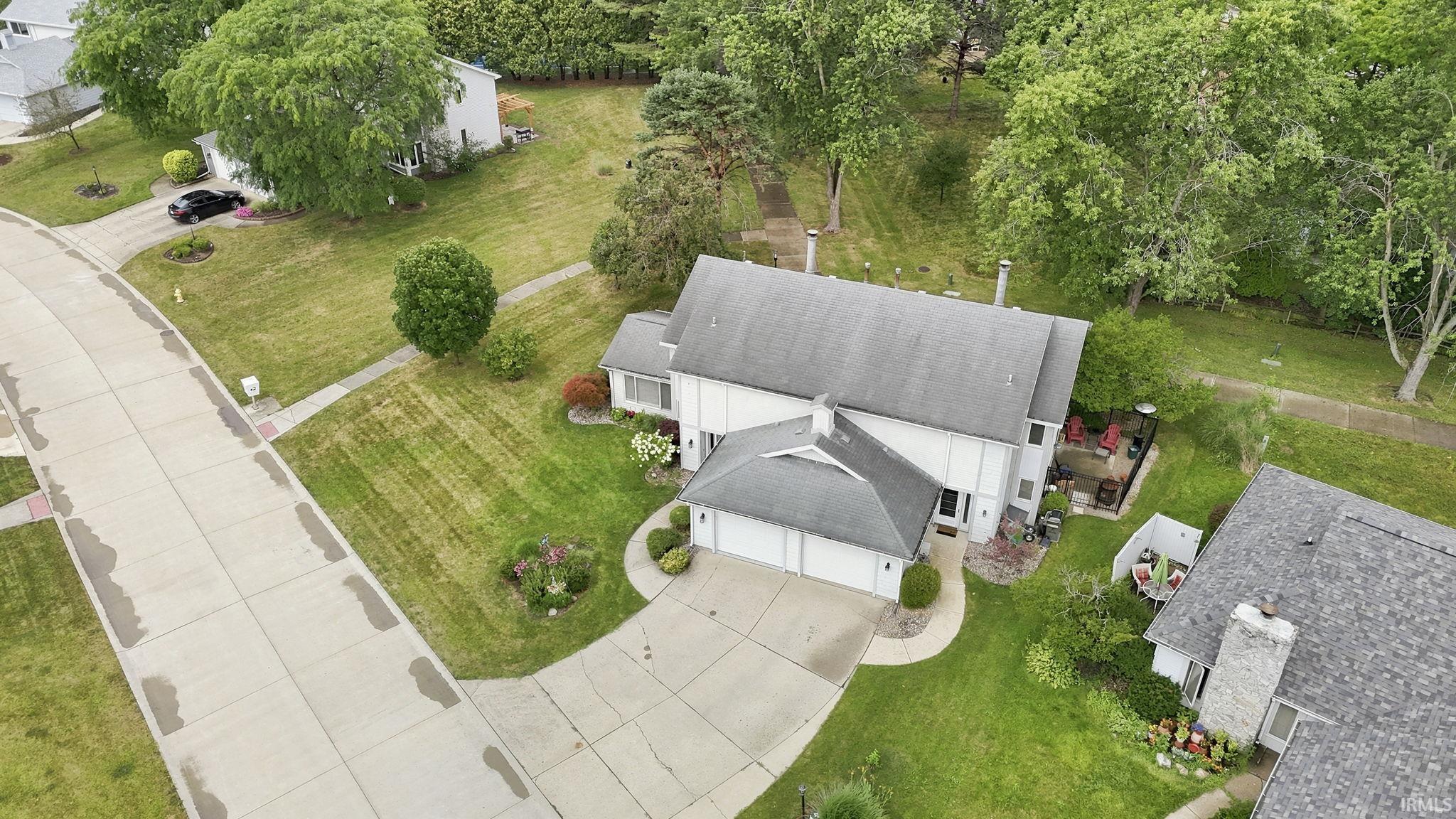 Aerial view of a residential property featuring a gray shingle roof, attached two-car garage, and a concrete driveway