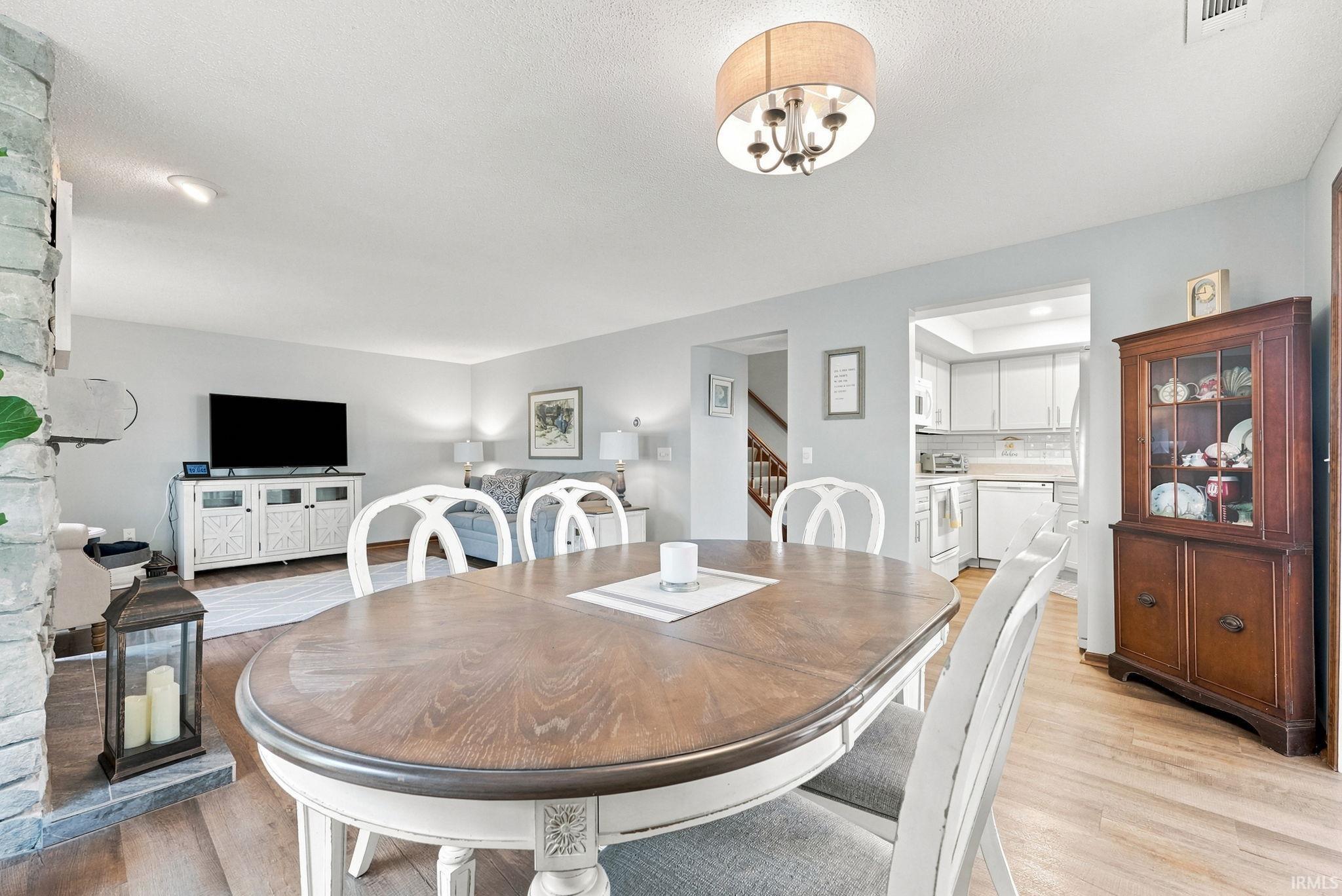 Dining area featuring wood-finish flooring, a contemporary drum chandelier, and a pass-through opening to the kitchen