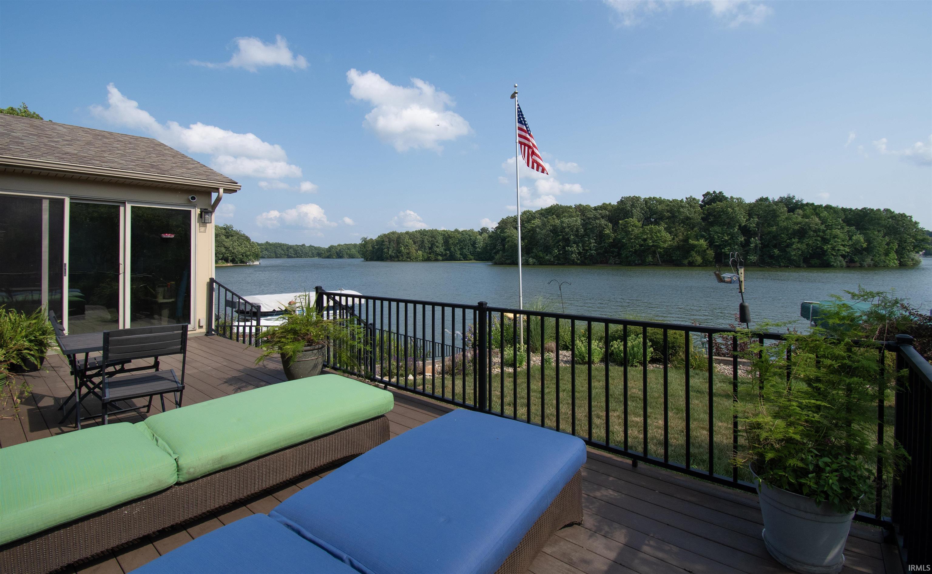 Spacious outdoor deck with a dark composite surface, black metal railings, and direct water frontage