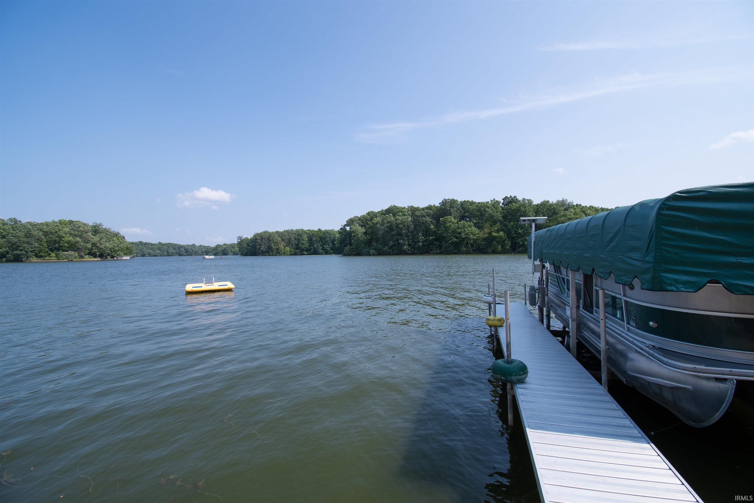 Lakefront property featuring a private dock and a wooded shoreline