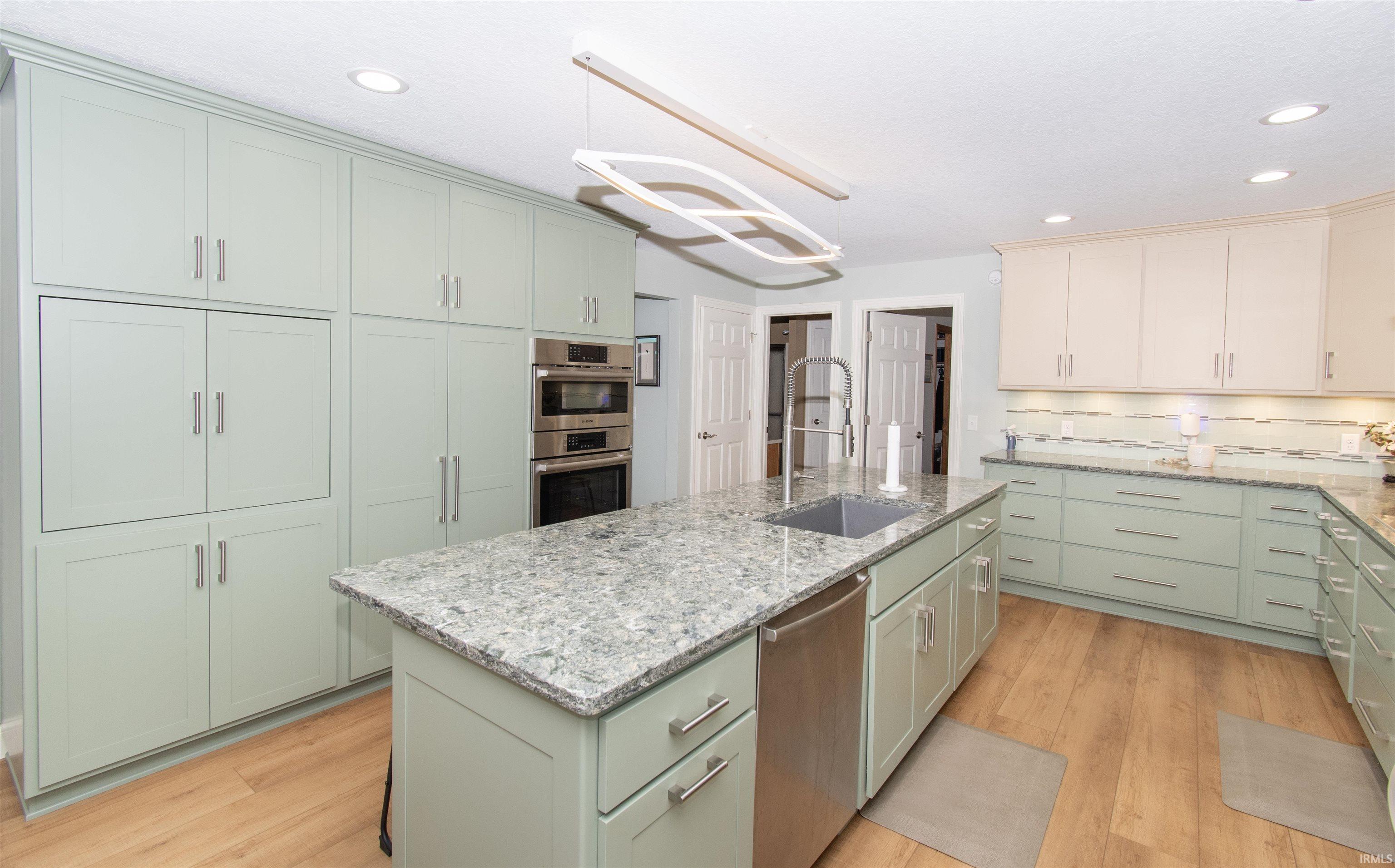 Kitchen featuring an expansive center island with an undermount sink and stainless steel dishwasher