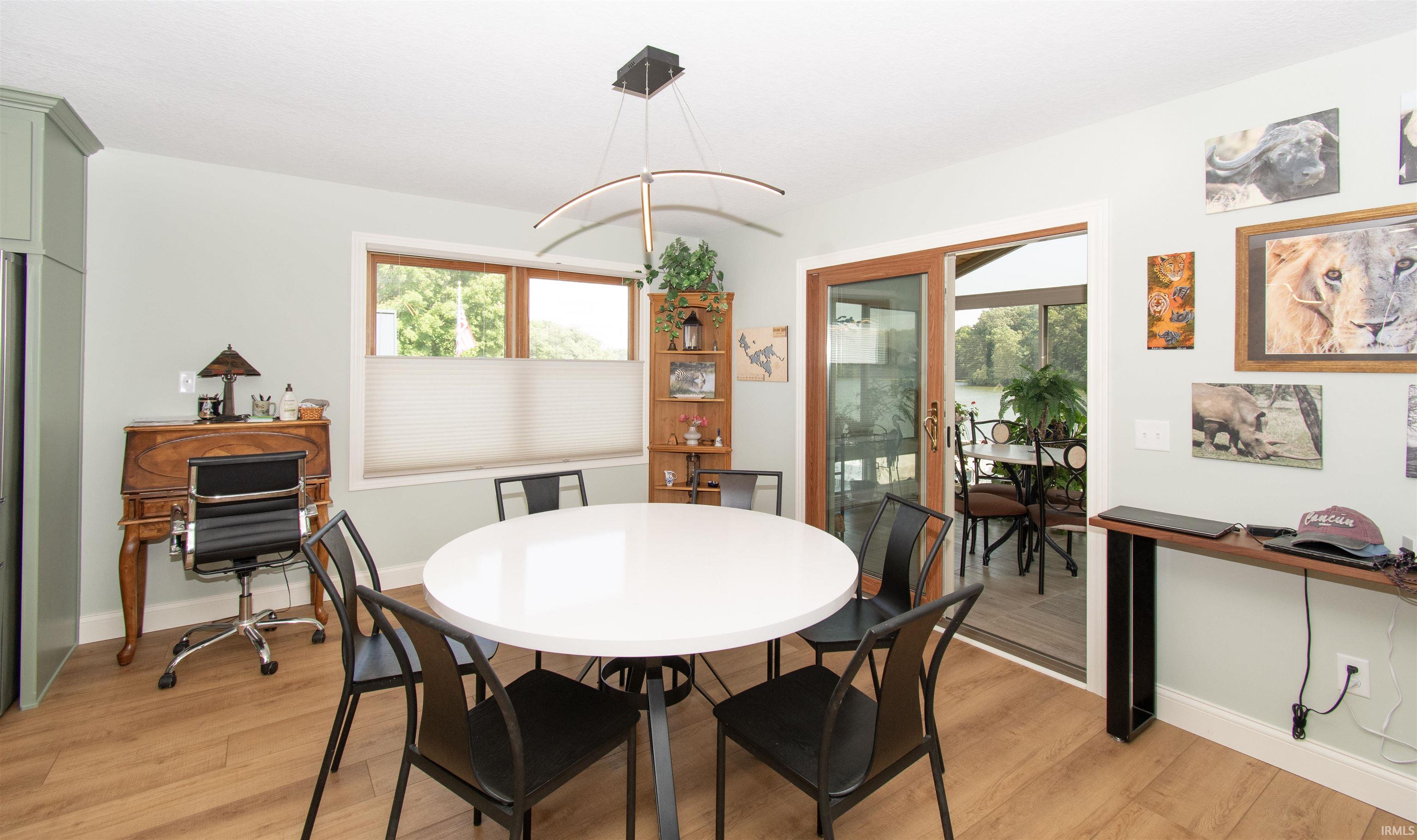 Open-concept room featuring light wood-finish flooring, a contemporary chandelier, and a sliding glass door opening to an enclosed patio