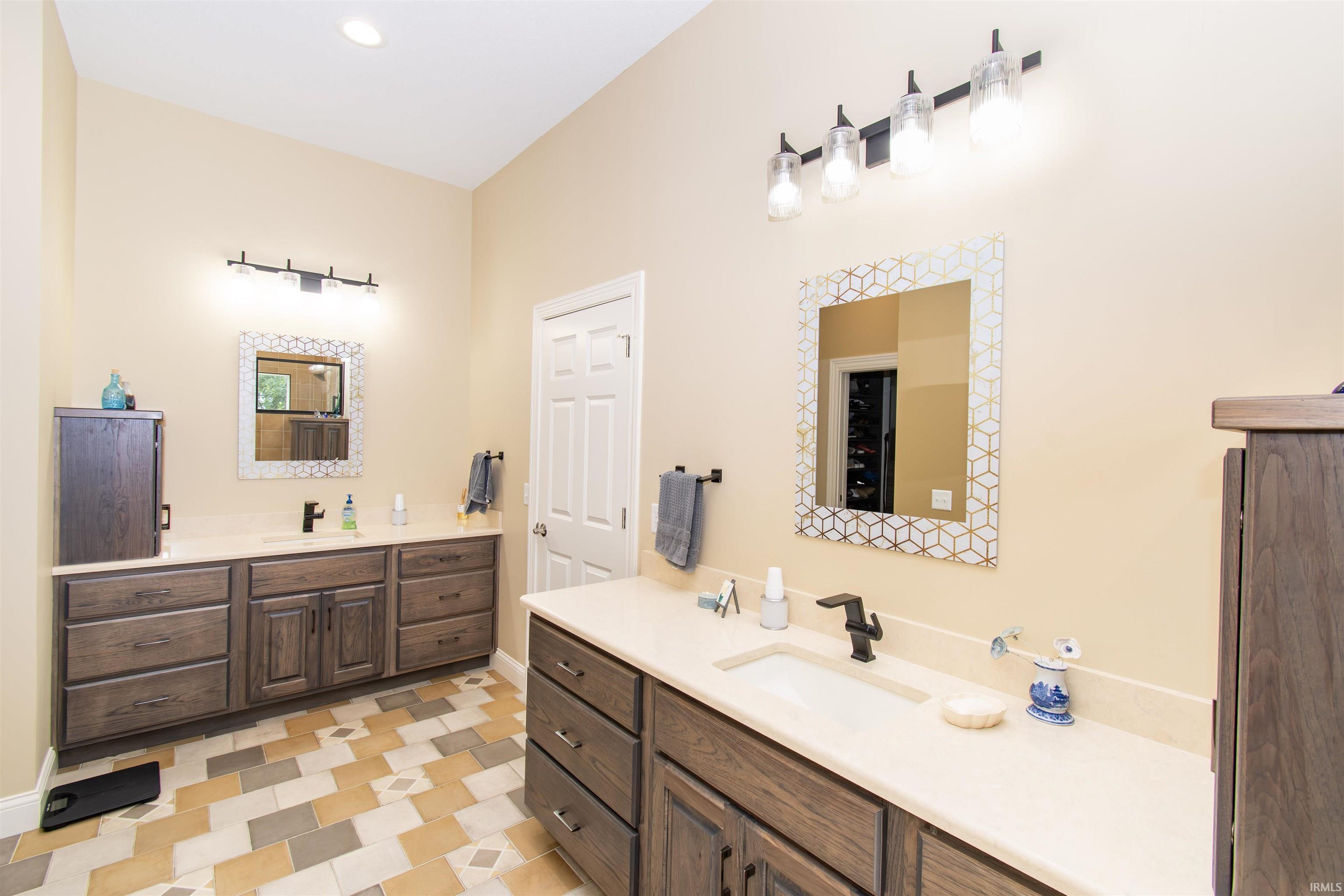 Bathroom featuring a dual vanity with wood-finish cabinetry and light-toned countertops
