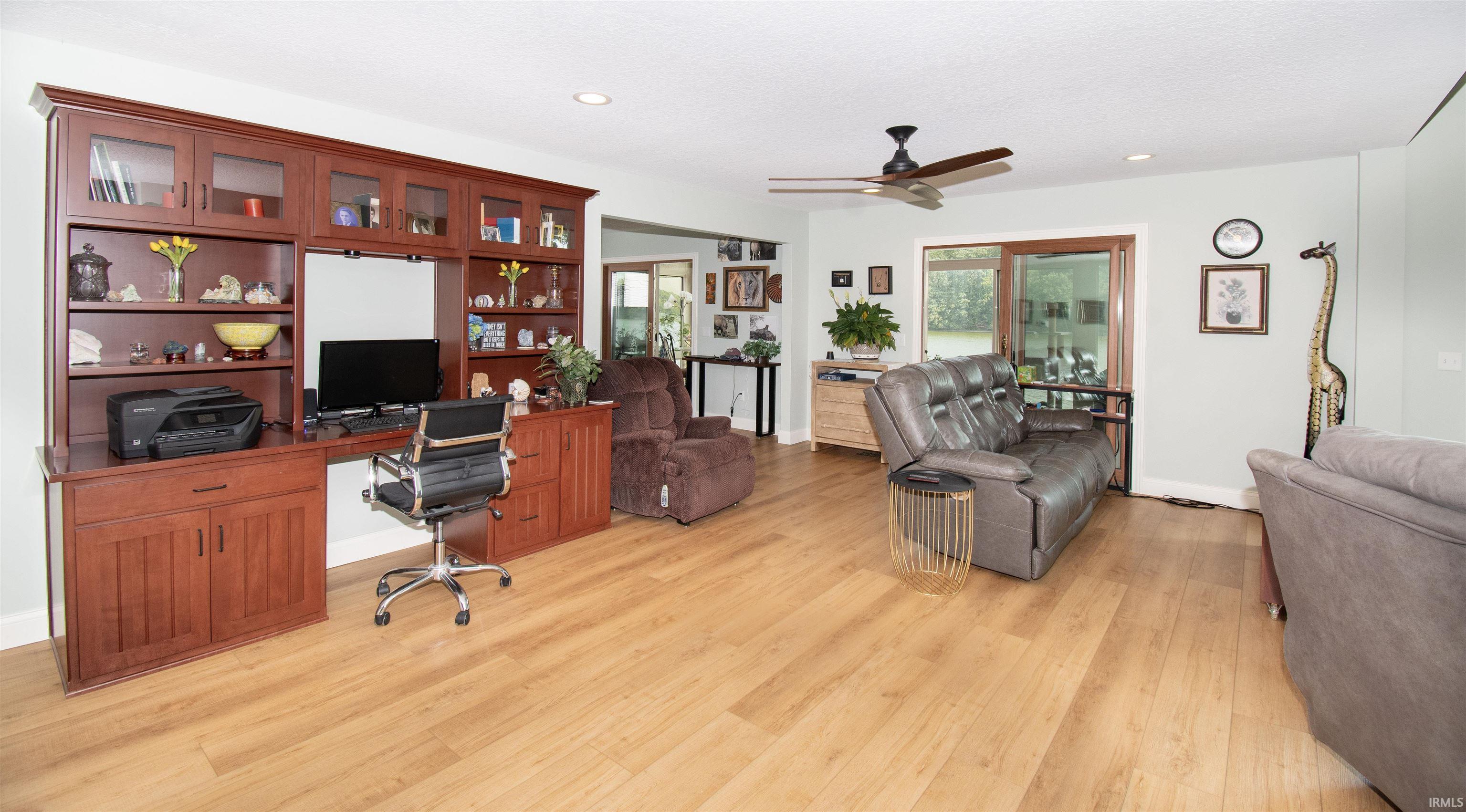 Integrated custom wood-finish cabinetry and desk, wood-finish flooring, recessed lighting, and a ceiling fan