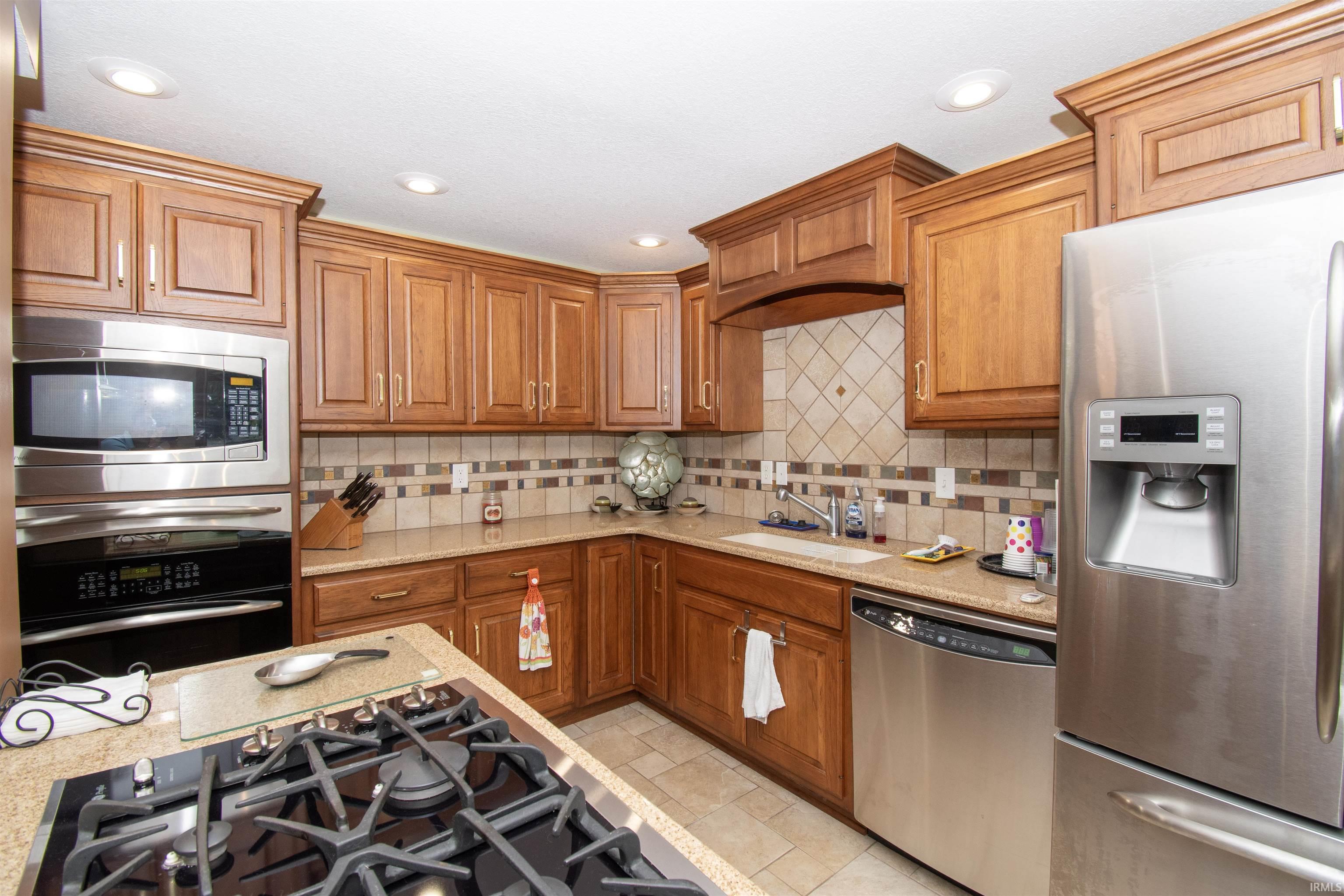 Kitchen featuring wood-finish cabinetry, stainless steel appliances, a built-in oven and microwave, and a tile backsplash