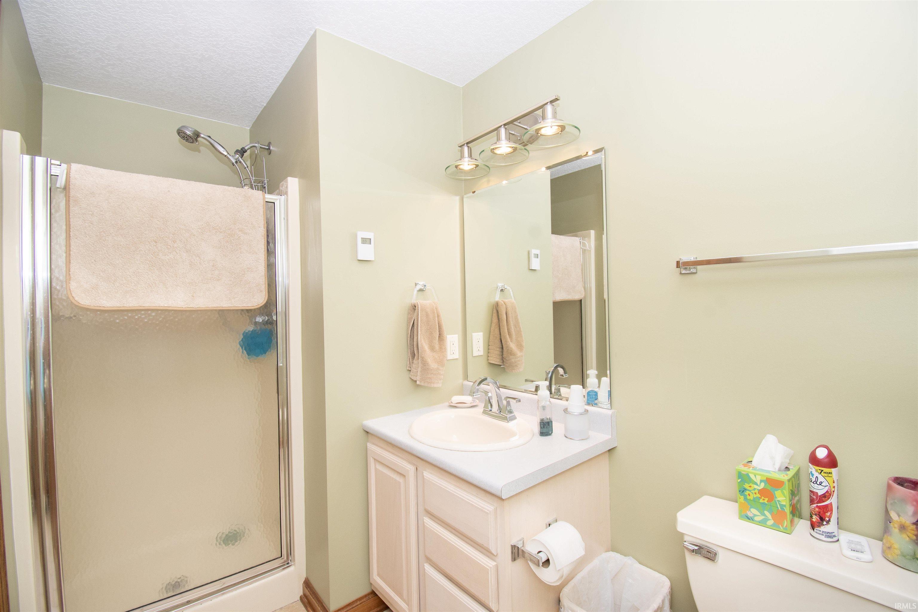Shower enclosure with a clear glass door, chrome shower head, single vanity with a laminate countertop, integrated sink, and chrome faucet