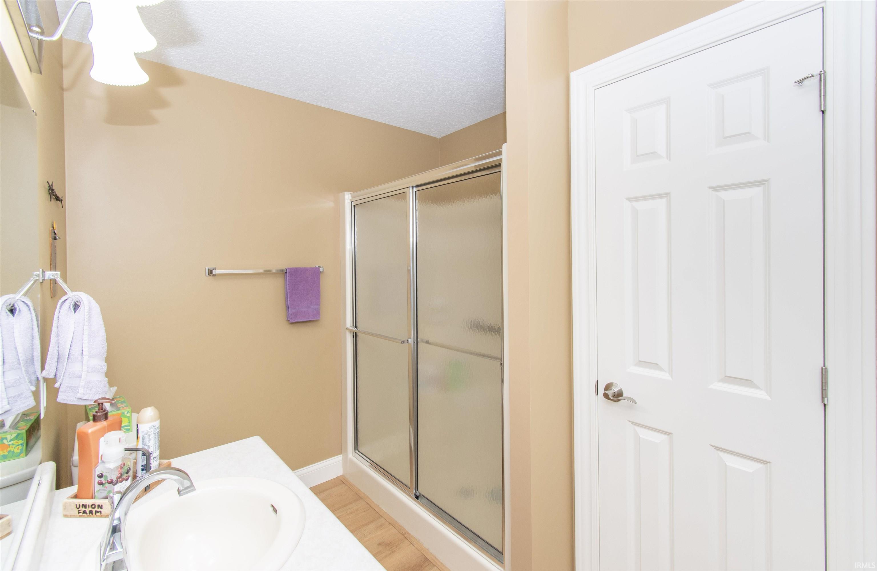 Bathroom featuring a white vanity with integrated sink, chrome faucet, and a shower with sliding glass doors